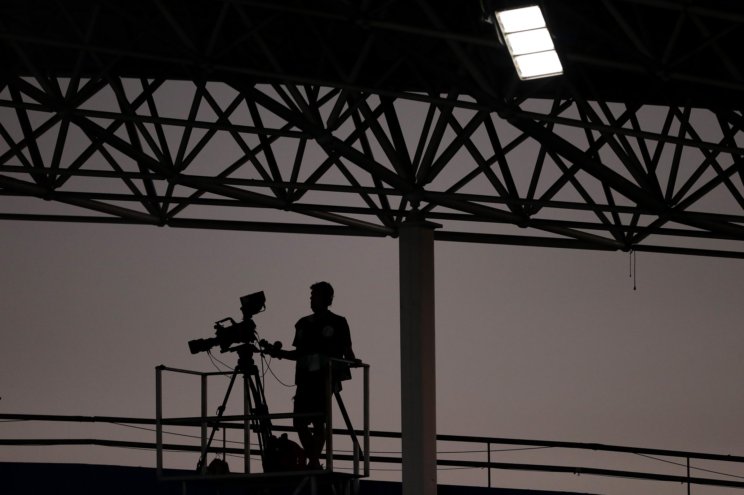 a camera operator is silhouetted by a dusk sky