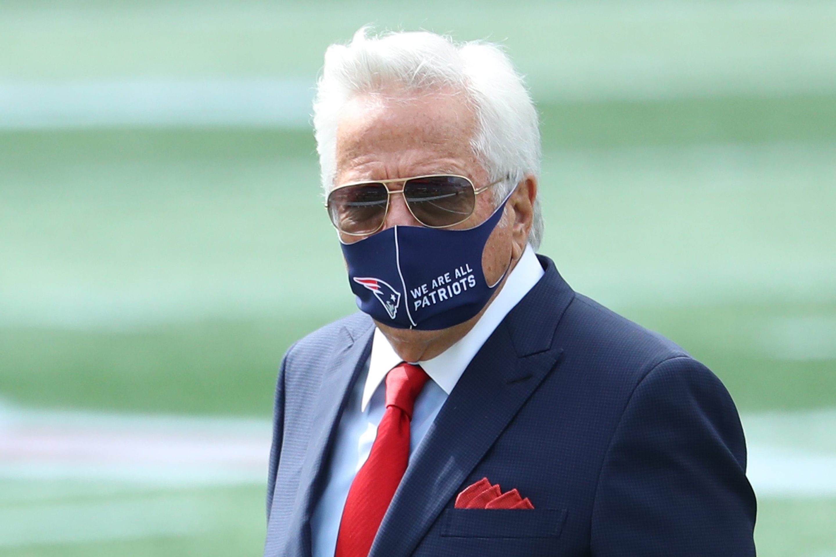 Patriots owner Robert Kraft wears a protective mask with "We Are All Patriots" stamped next to a Patriots logo.