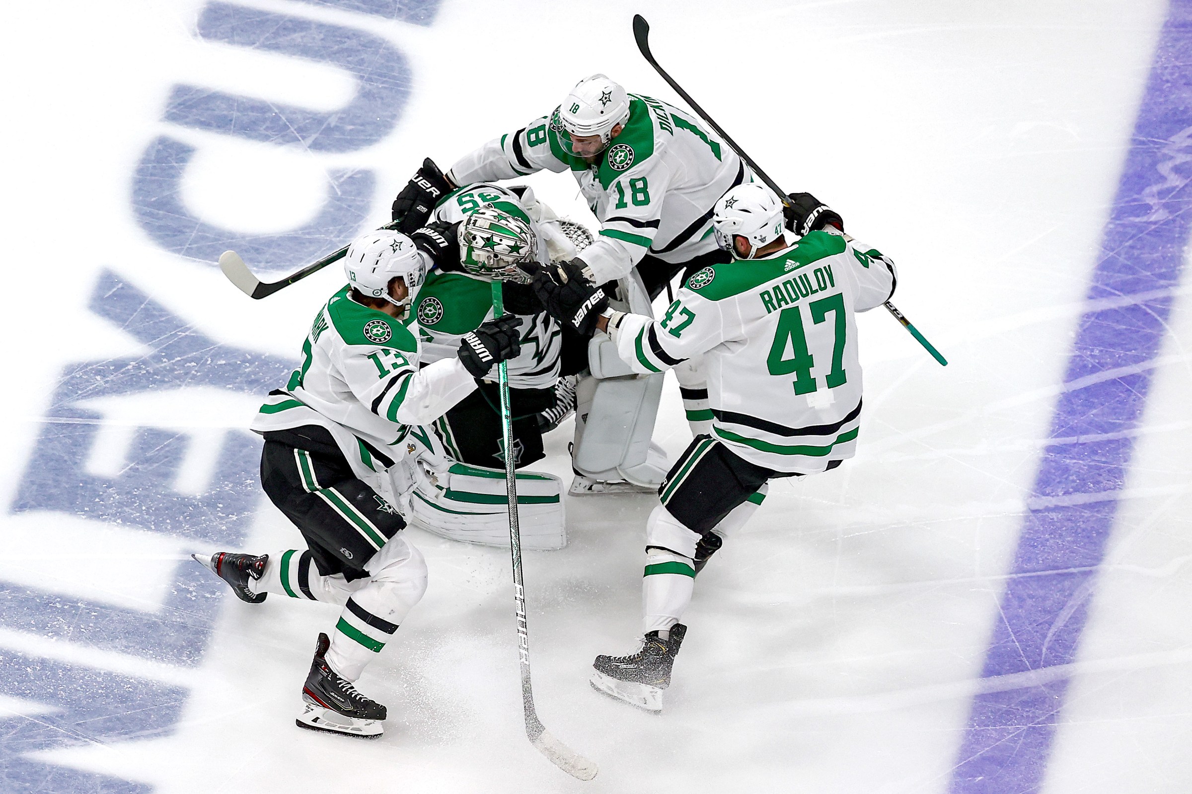 Jason Dickinson #18, Alexander Radulov #47 and Mattias Janmark #13 of the Dallas Stars grab on to Anton Khudobin #35 as they celebrate their 3-2 overtime victory against the Vegas Golden Knights to win Game Five of the Western Conference Final