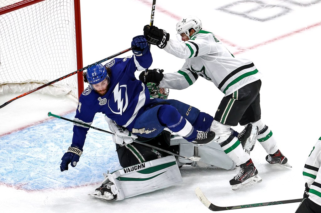 Brayden Point #21 of the Tampa Bay Lightning is checked into Anton Khudobin #35 by Miro Heiskanen #4 of the Dallas Stars