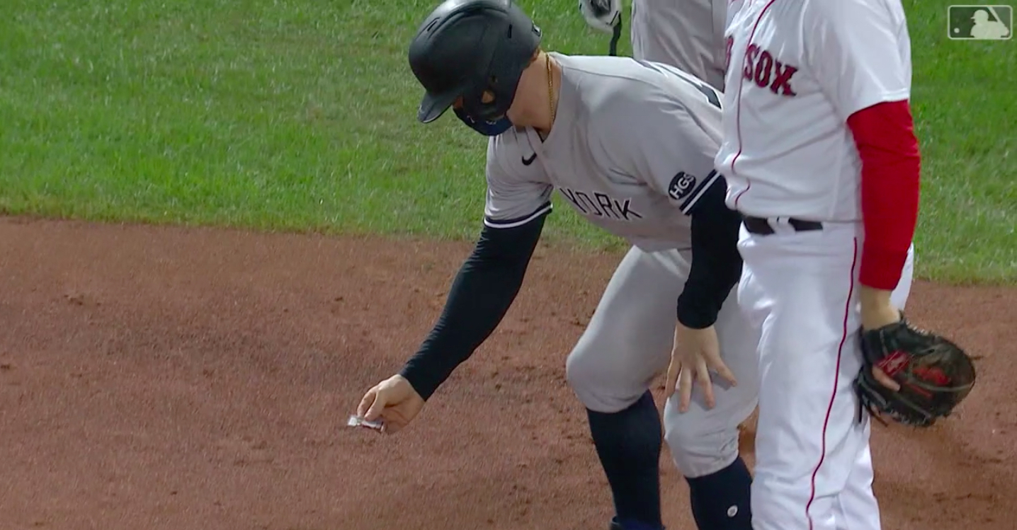 Yankees player Clint Frazier aids a bug on the infield dirt.