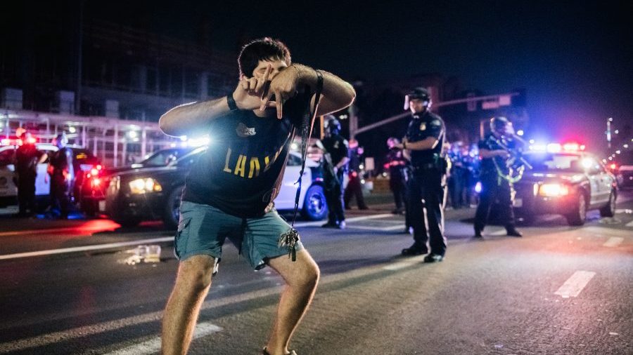 A Lakers fan celebrates in the streets of Los Angeles in front of many policemen.