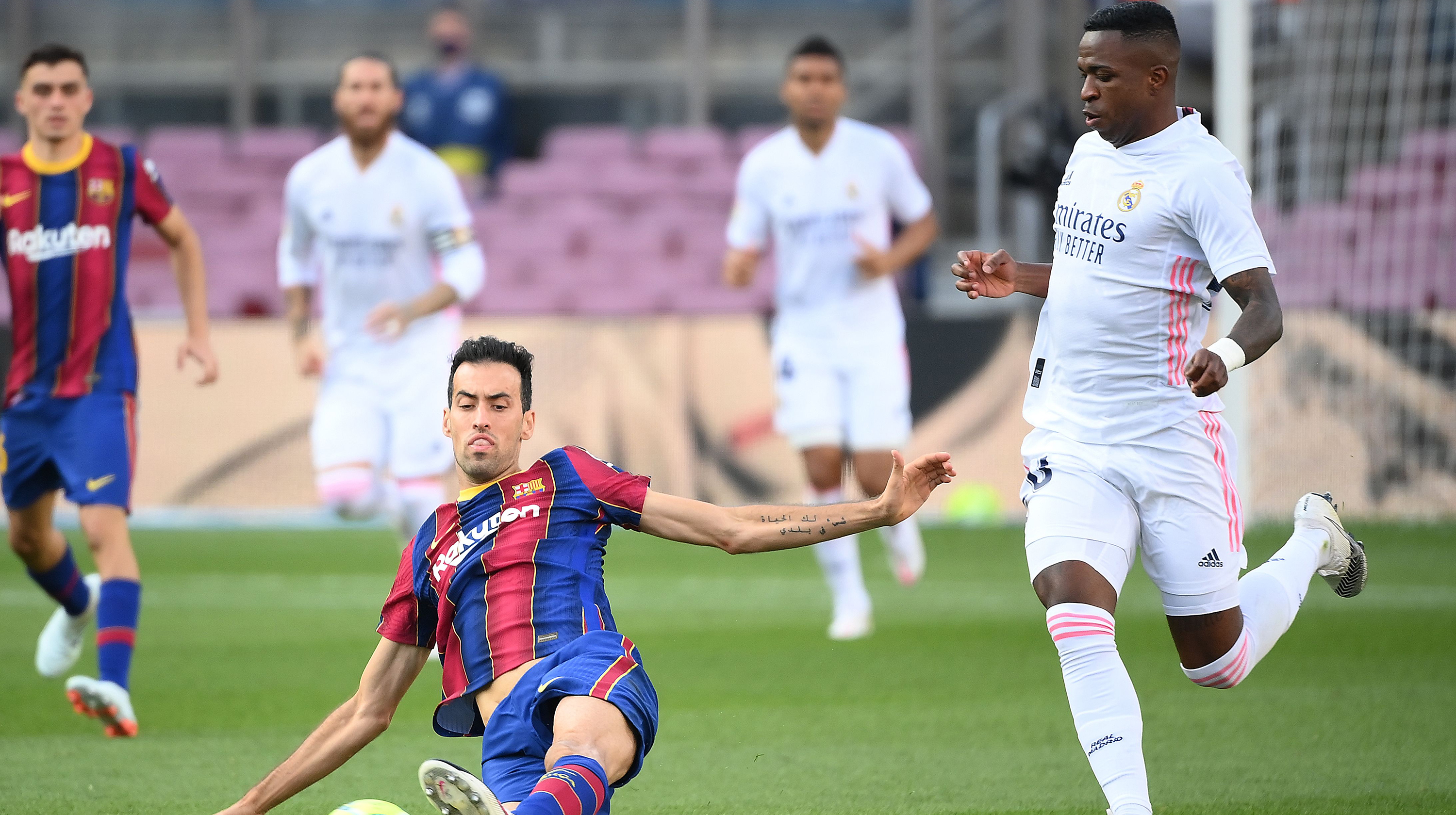 Real Madrid's Brazilian forward Vinicius Junior (R) challenges Barcelona's Spanish midfielder Sergio Busquets during the Spanish League football match between Barcelona and Real Madrid