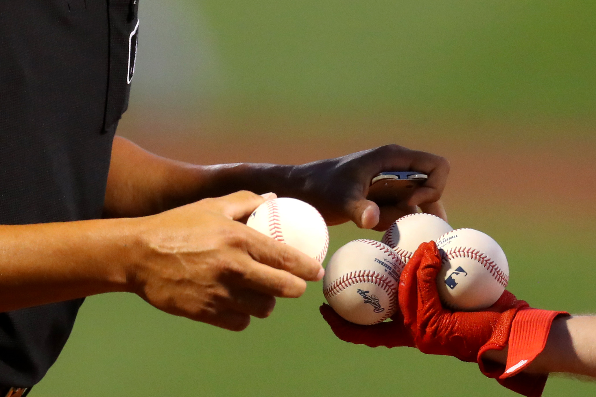 Baseball players handle some baseballs.
