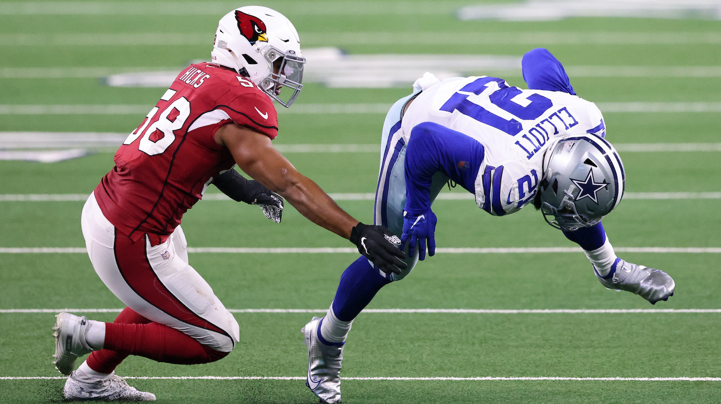 ARLINGTON, TEXAS - OCTOBER 19: Ezekiel Elliott #21 of the Dallas Cowboys is tackled by Jordan Hicks #58 of the Arizona Cardinals during the second quarter at AT&amp;T Stadium on October 19, 2020, in Arlington, Texas. (Photo by Ronald Martinez/Getty Images)