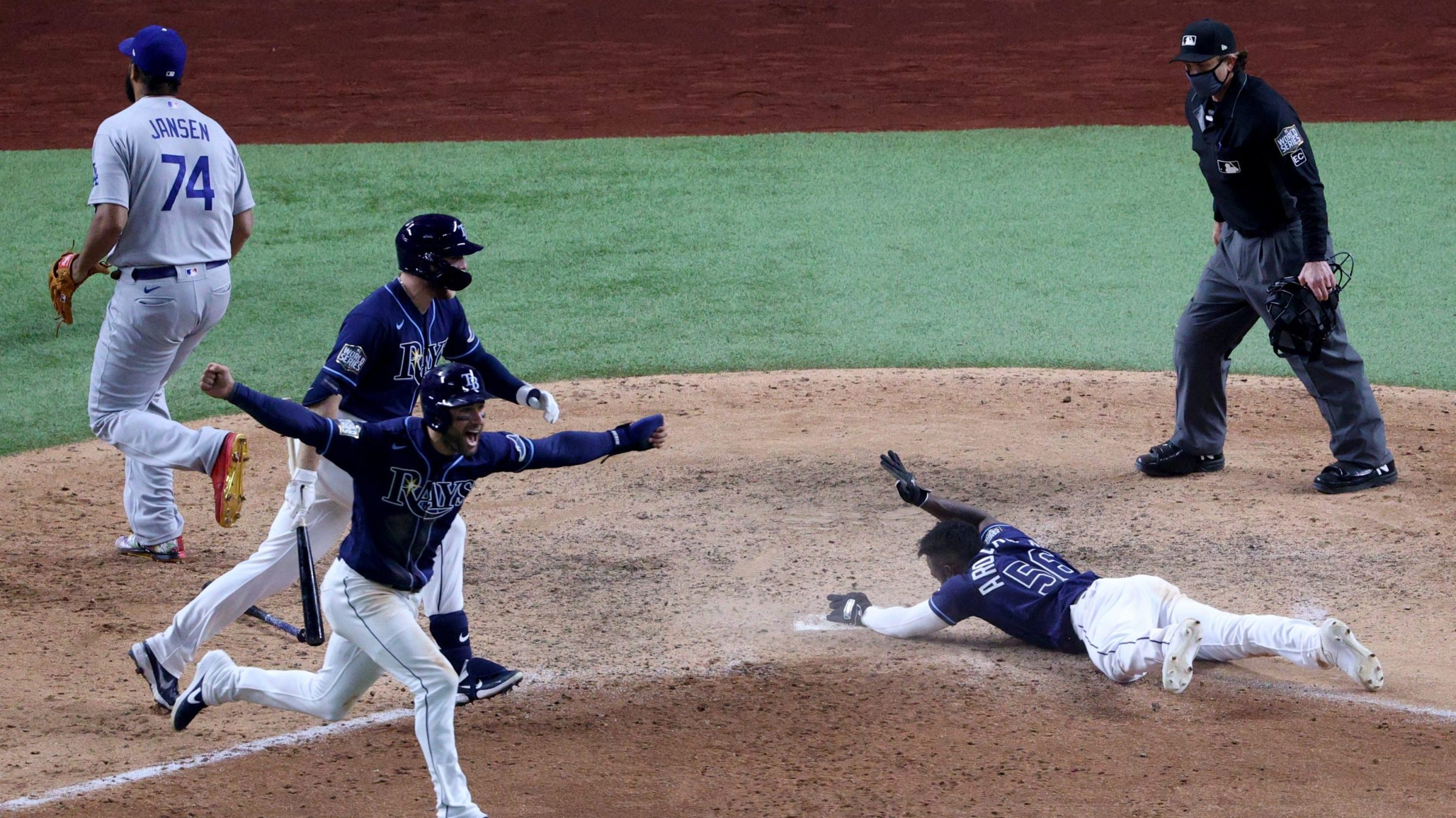 Randy Arozarena #56 of the Tampa Bay Rays slides into home plate during the ninth inning to score the game winning run to give his team the 8-7 victory as Kevin Kiermaier celebrates against the Los Angeles Dodgers in Game Four of the 2020 MLB World Series