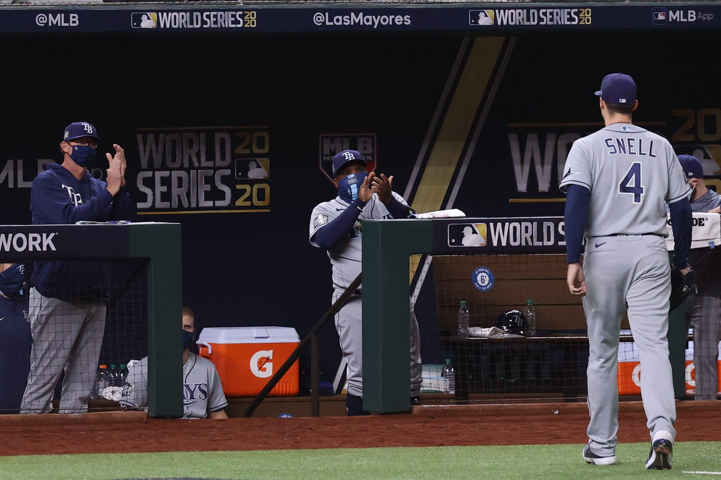 Blake Snell #4 of the Tampa Bay Rays is congratulated by pitching coach Kyle Snyder and third base coach Rodney Linares after being taken out of the game
