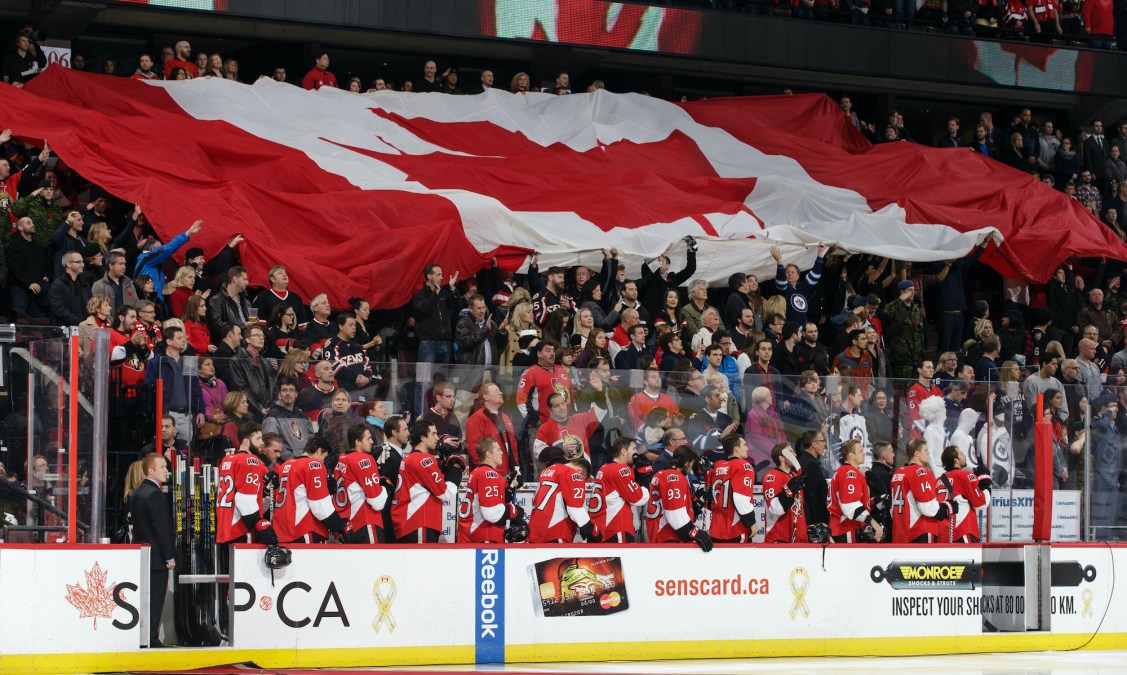 OTTAWA, ON - NOVEMBER 8: Members of the Ottawa Senators stand as a large Canadian flag is passed along in the stands during the singing of the national anthem prior to an NHL game against the Winnipeg Jets at Canadian Tire Centre on November 8, 2014 in Ottawa, Ontario, Canada. (Photo by Jana Chytilova/Freestyle Photography/Getty Images) *** Local Caption ***