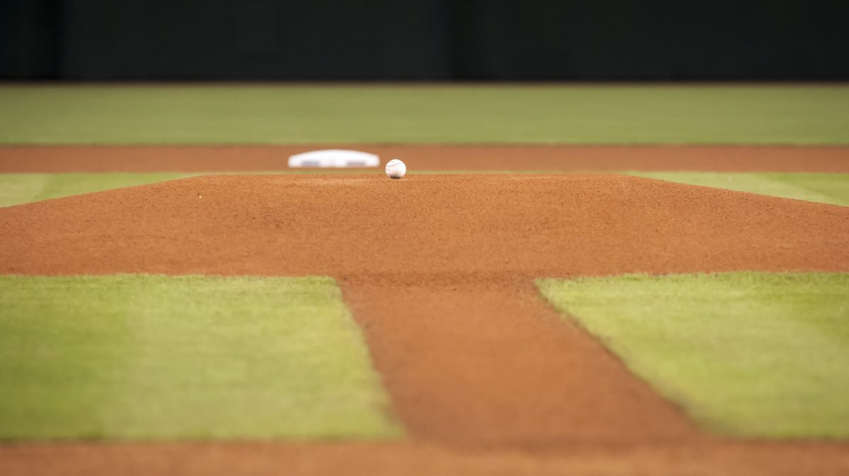 A baseball sitting on an empty baseball field.