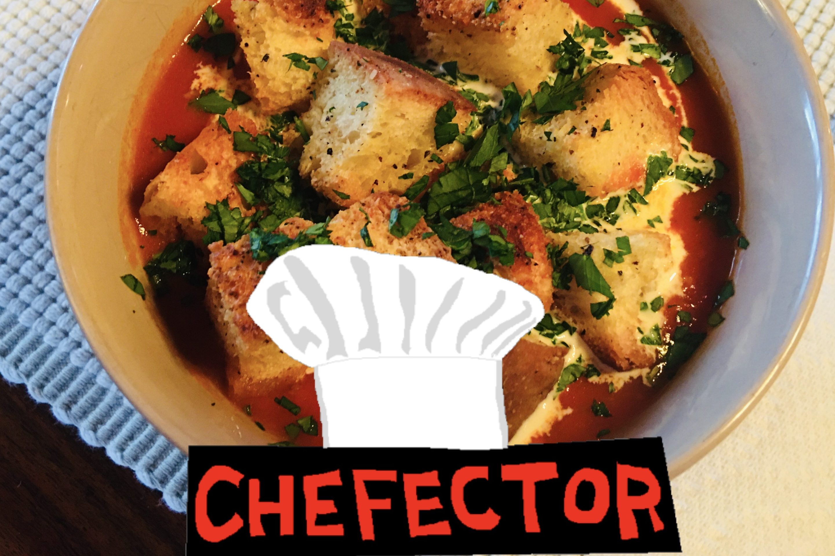 A bowl of tomato soup with croutons and herbs