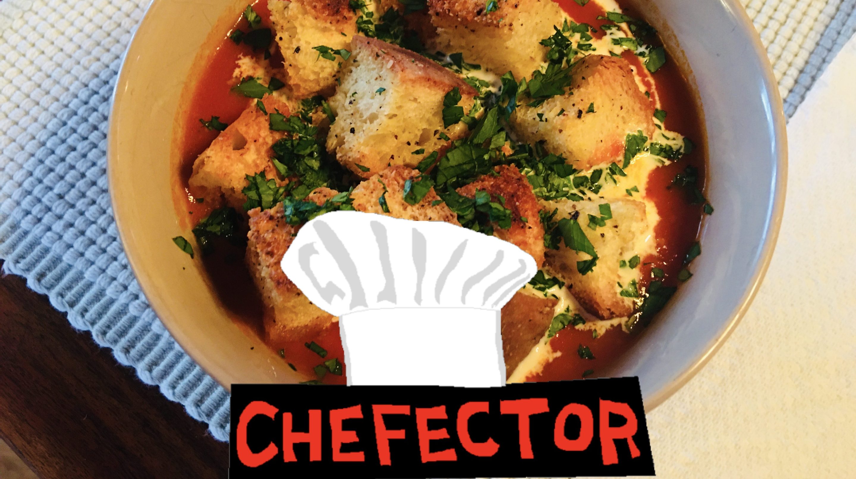 A bowl of tomato soup with croutons and herbs