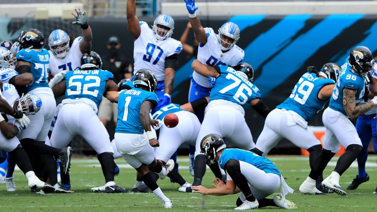 Jaguars kicker Jon Brown attempts a field goal. Lions players have their hands up to try to block it.