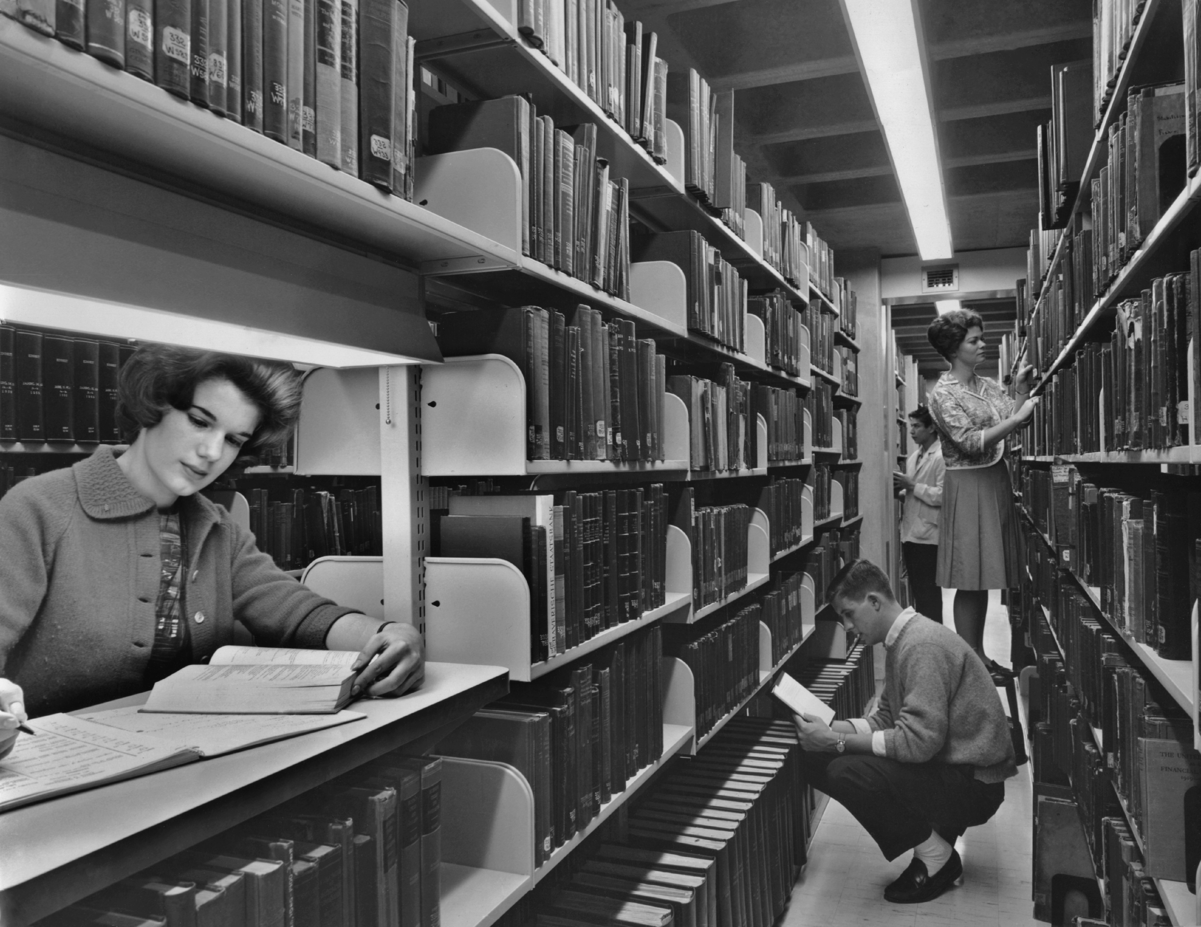 a few students read in a crowded library