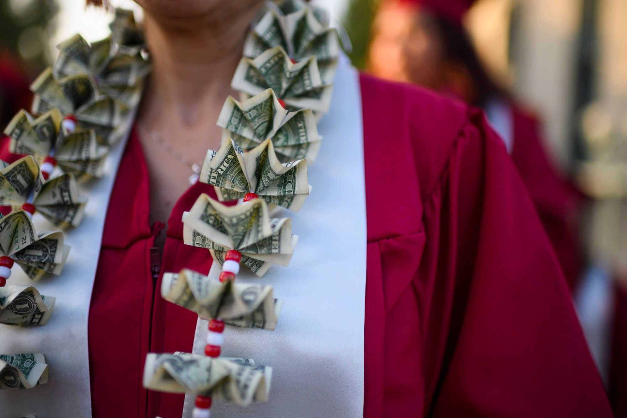 A graduating student wears a money lei, a necklace made of US dollar bills, at the Pasadena City College graduation ceremony, June 14, 2019, in Pasadena, California. - With 45 million borrowers owing $1.5 trillion, the student debt crisis in the United States has exploded in recent years and has become a key electoral issue in the run-up to the 2020 presidential elections. "Somebody who graduates from a public university this year is expected to have over $35,000 in student loan debt on average," said Cody Hounanian, program director of Student Debt Crisis, a California NGO that assists students and is fighting for reforms.