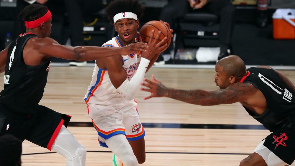 Shai Gilgeous-Alexander drives toward the basket between Houston Rockets defenders