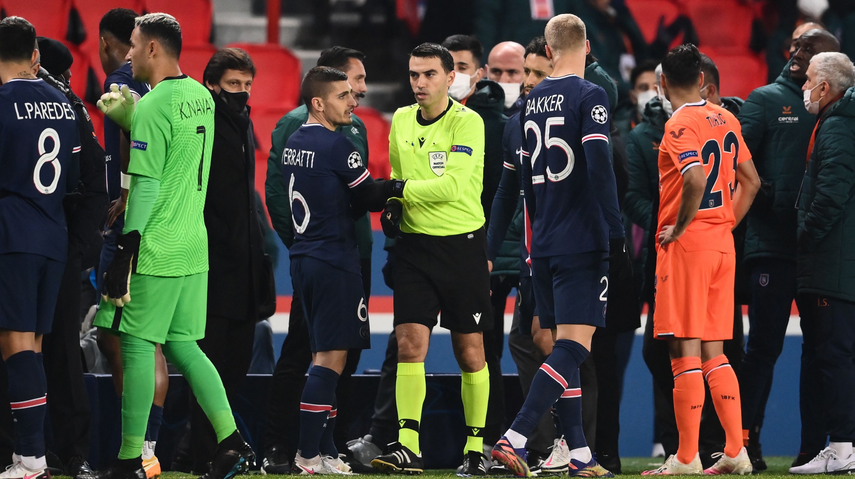 Romanian referee Ovidiu Hategan (in yellow) passes by Paris Saint-Germain's Italian midfielder Marco Verratti (CL) after the game was suspended amid allegations of racism by one of the match officials during the UEFA Champions League group H football match between Paris Saint-Germain (PSG) and Istanbul Basaksehir FK