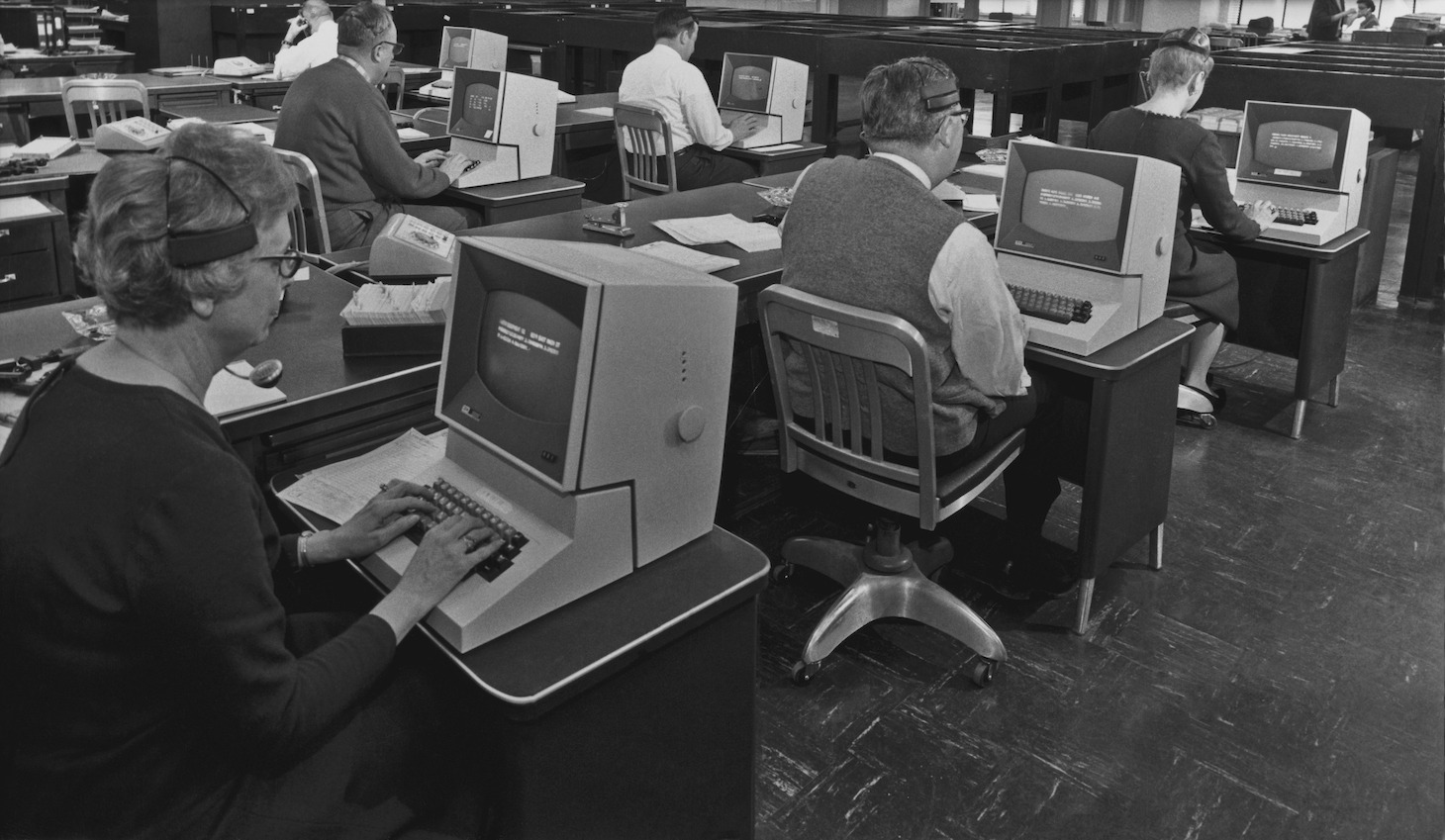 A group of office workers using telephone headsets and computers circa 1965 (Photo by Authenticated News/Archive Photos/Getty Images)