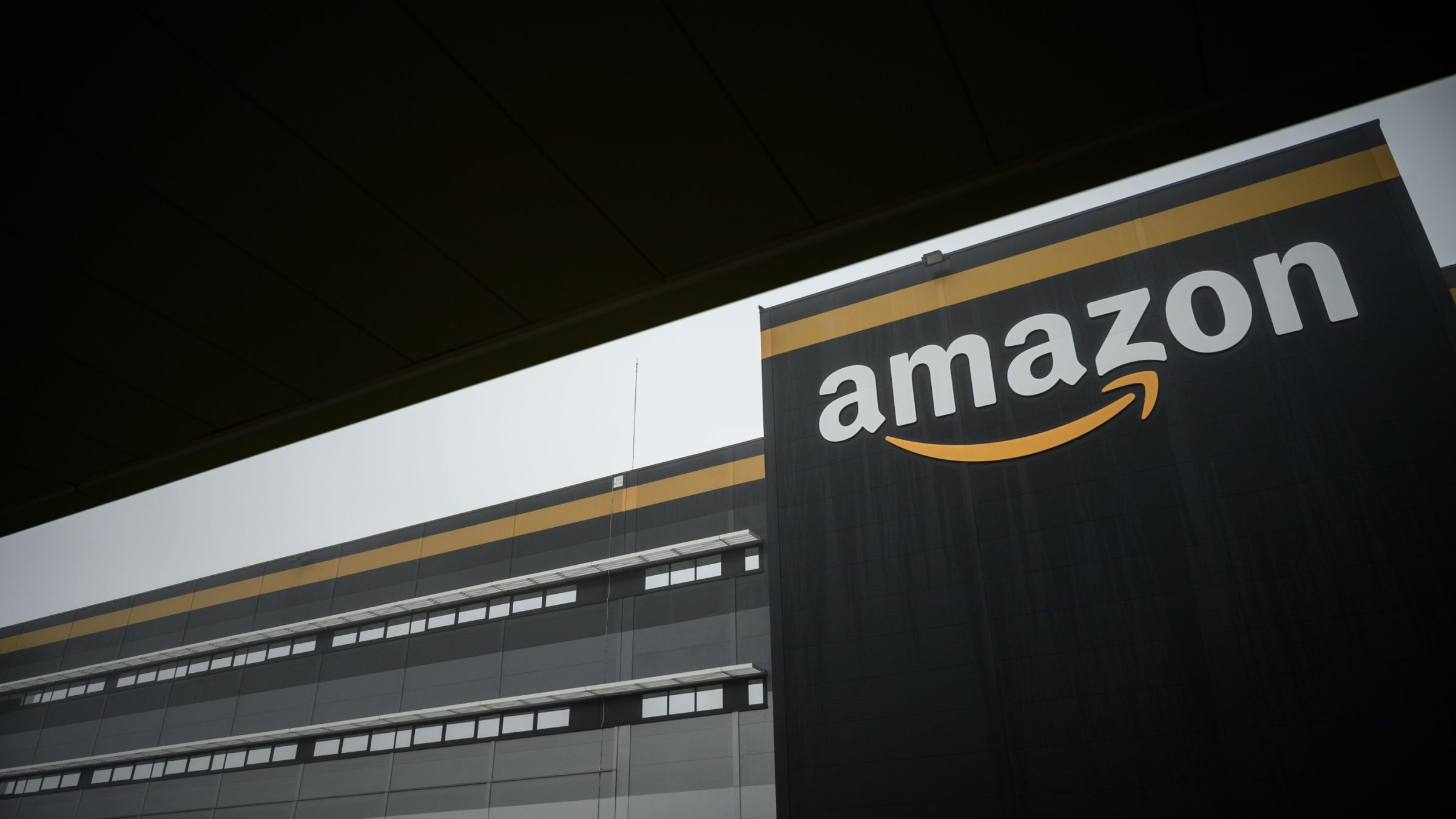 The Amazon logo at a new Amazon warehouse, set against a black sky.