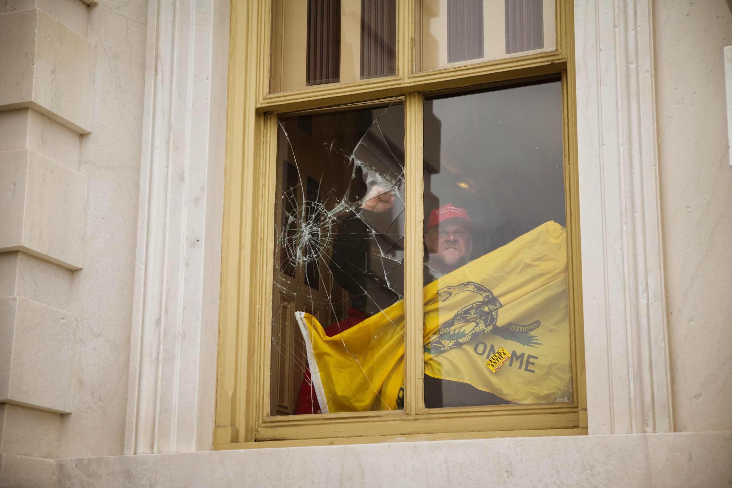 A member of a pro-Trump mob shatters a window with his fist from inside the Capitol Building after breaking into it on January 6, 2021 in Washington, DC.