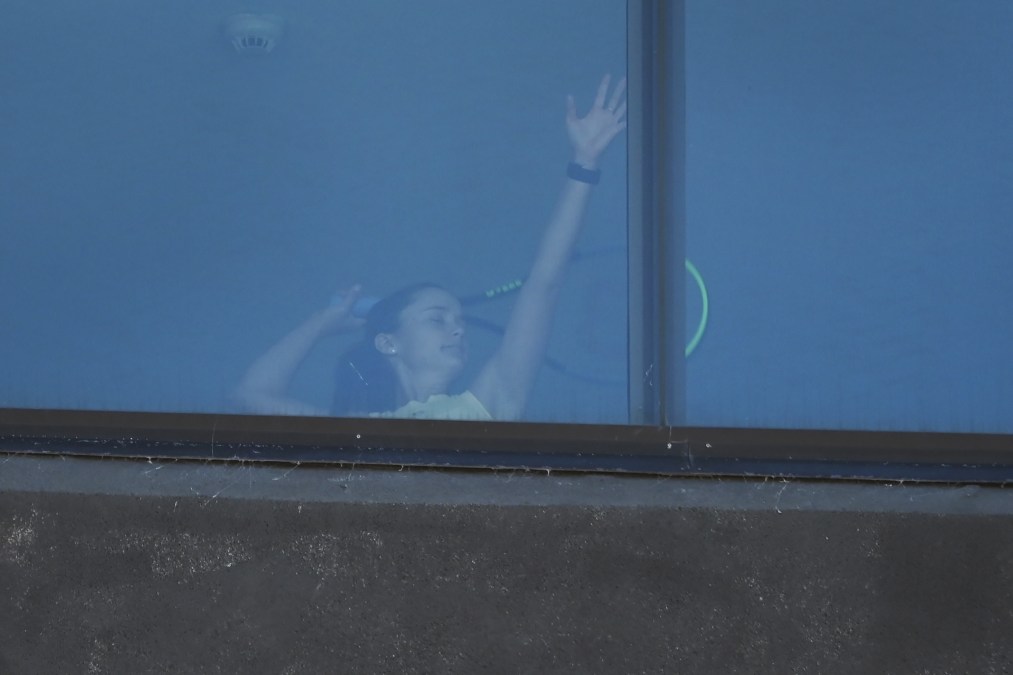 A tennis player is seen practicing serve inside her hotel room.