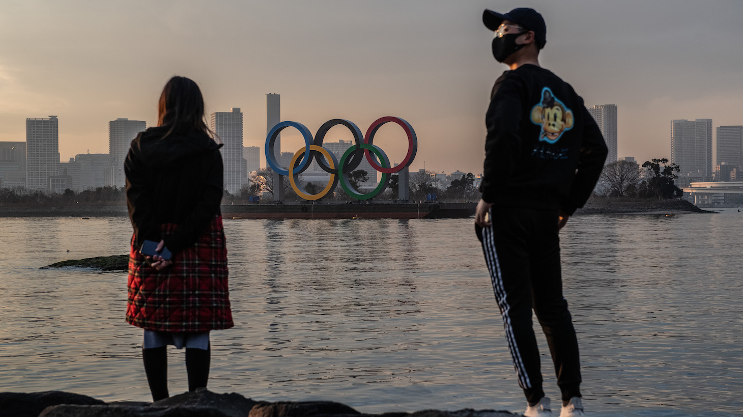 TOKYO, JAPAN - JANUARY 22: A woman and a man wearing a face mask view the Olympic Rings on January 22, 2021 in Tokyo, Japan. With just six months to go until the start of the Games, it has been reported that the Japanese authorities have privately concluded that the Olympics could not proceed due to the ongoing Covid-19 coronavirus pandemic. Spokesmen from the IOC and Japanese government have since rejected the report. (Photo by Carl Court/Getty Images)