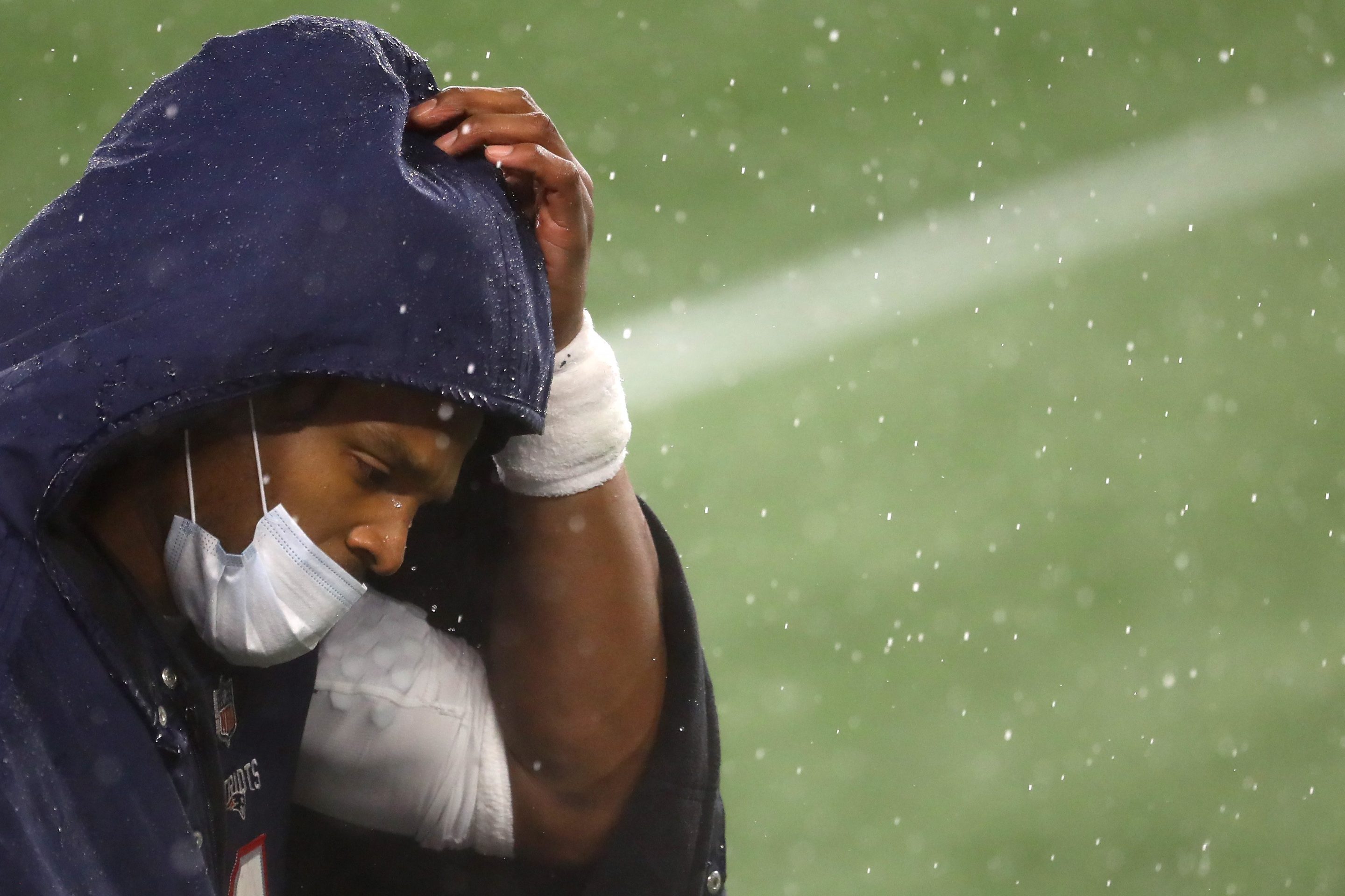 Cam Newton, quarterback, of the New England Patriots, looks on from the sideline wearing a mask and rain jacket during the game against the Baltimore Ravens at Gillette Stadium on November 15, 2020 in Foxborough, Massachusetts.