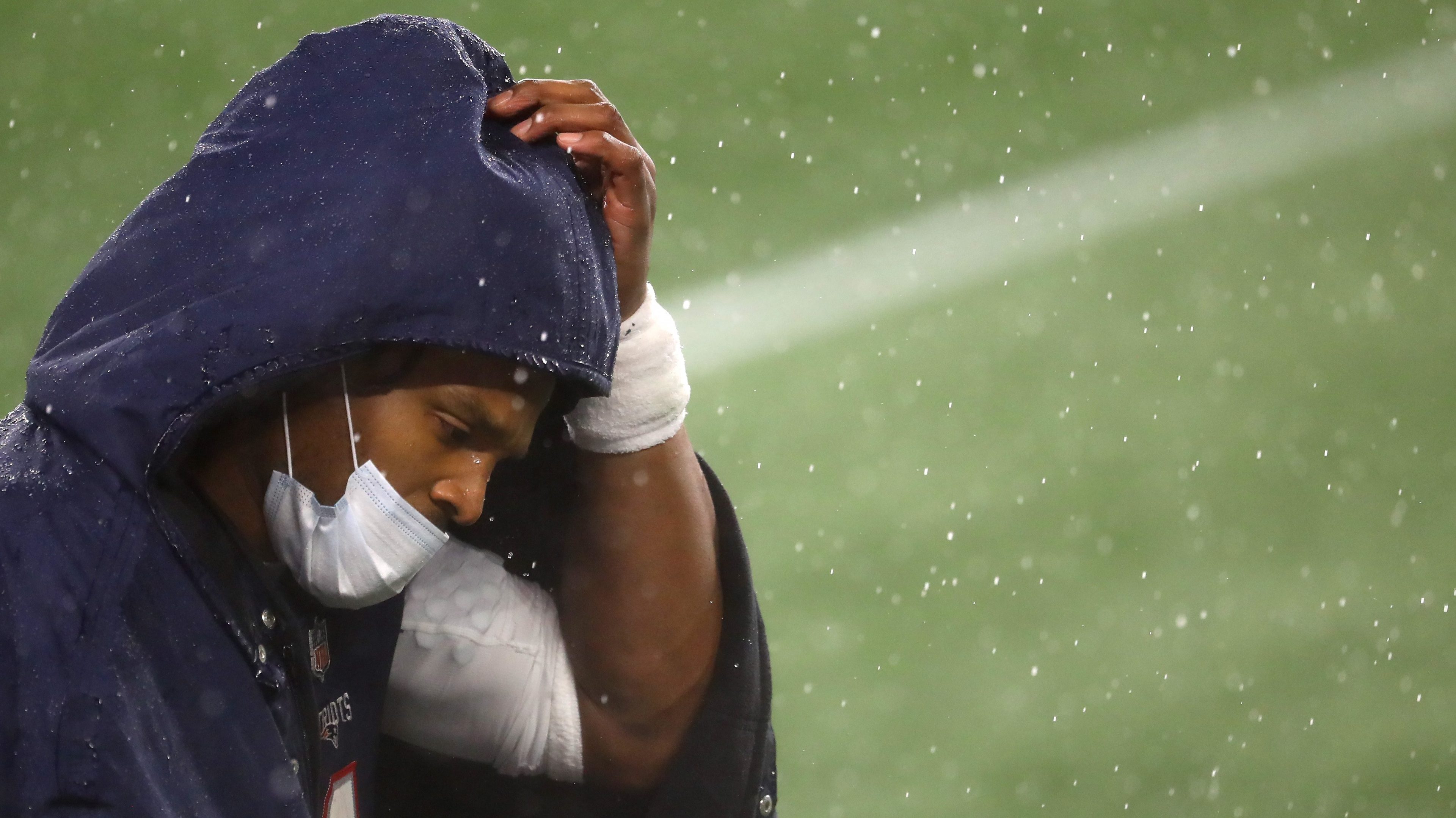 Cam Newton, quarterback, of the New England Patriots, looks on from the sideline wearing a mask and rain jacket during the game against the Baltimore Ravens at Gillette Stadium on November 15, 2020 in Foxborough, Massachusetts.