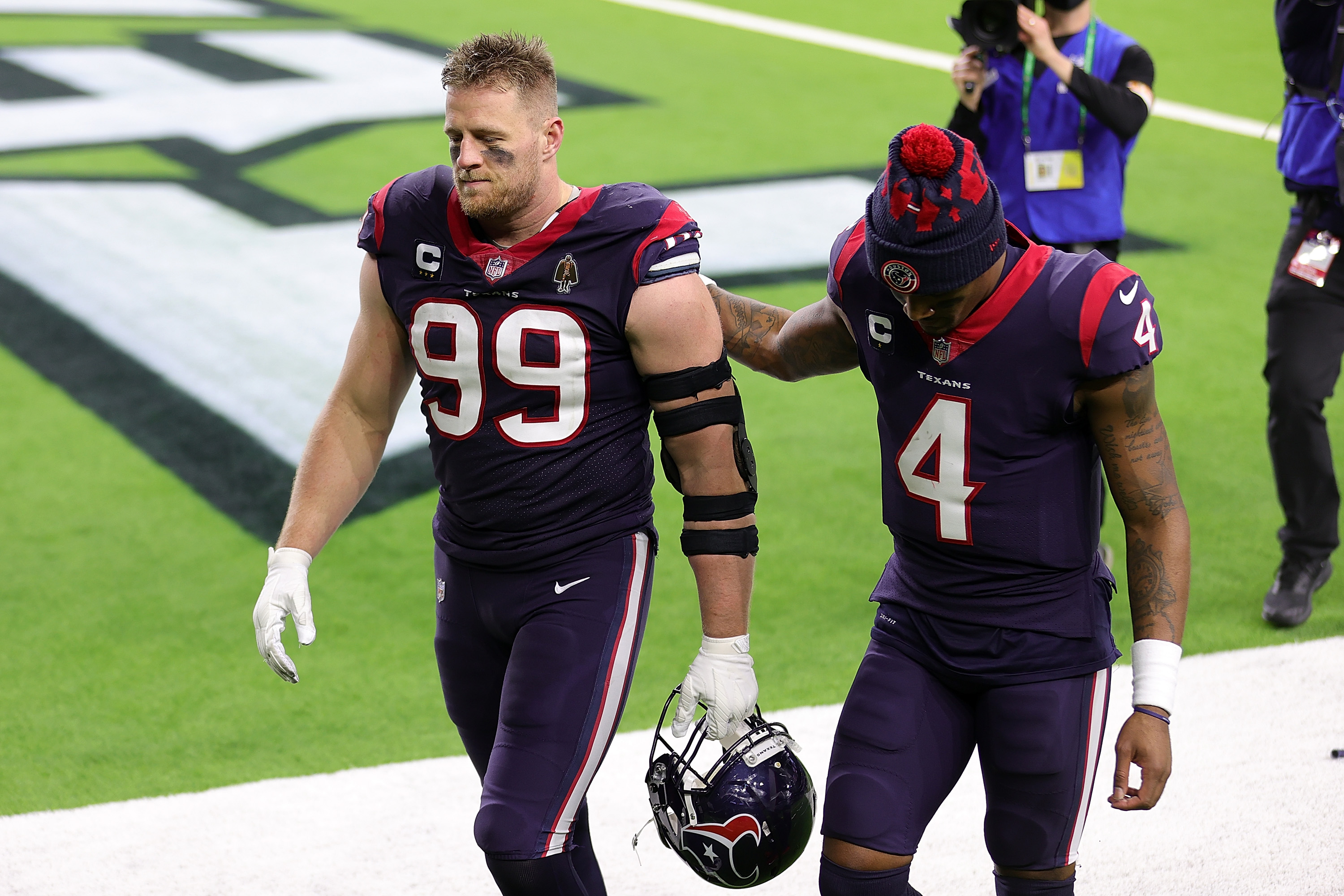 J.J. Watt #99 of the Houston Texans walks off the field with Deshaun Watson