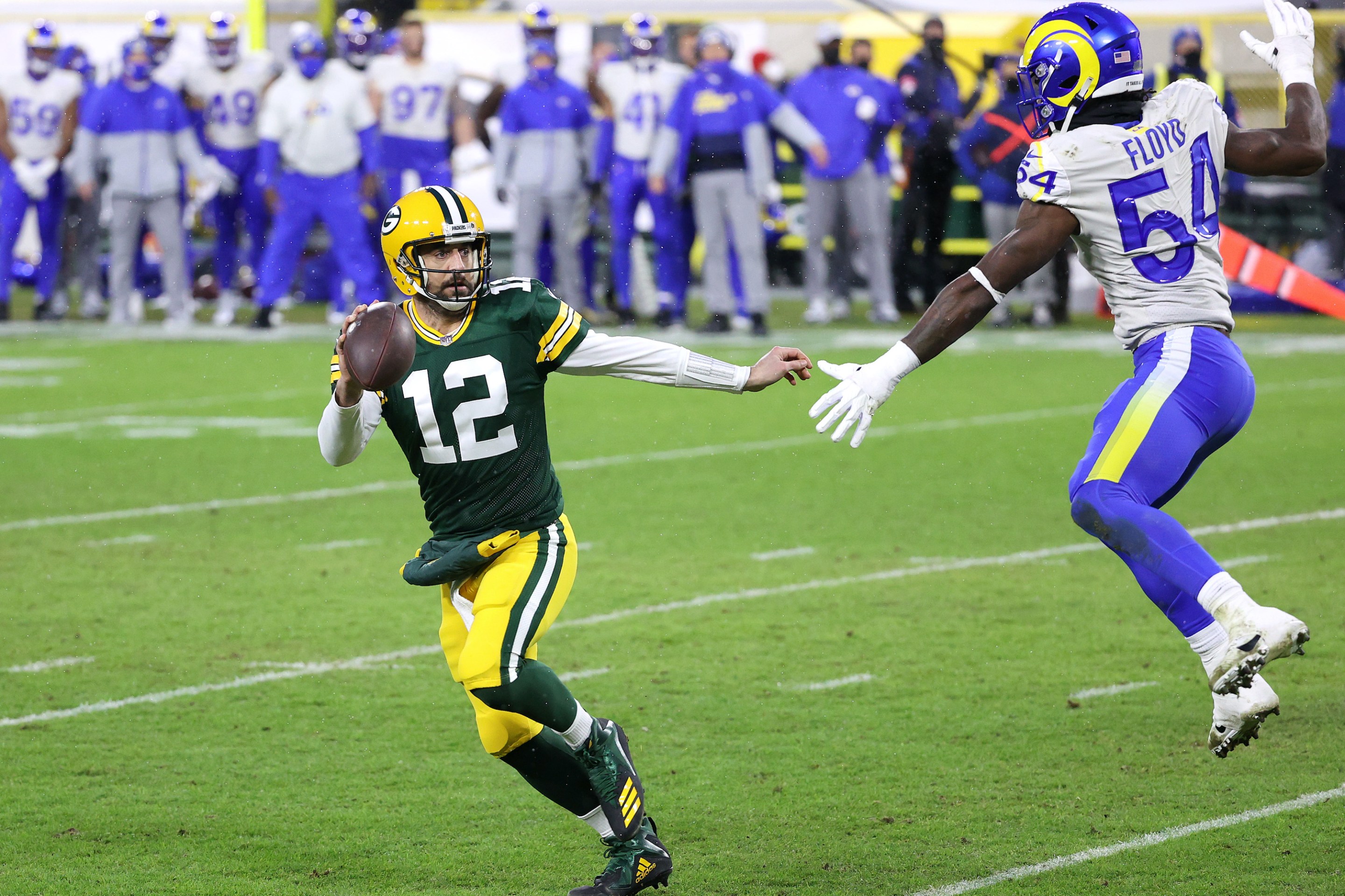 Aaron Rodgers #12 of the Green Bay Packers runs against Leonard Floyd #54 of the Los Angeles Rams for a 1-yard touchdown in the second quarter during the NFC Divisional Playoff game at Lambeau Field on January 16, 2021 in Green Bay, Wisconsin.