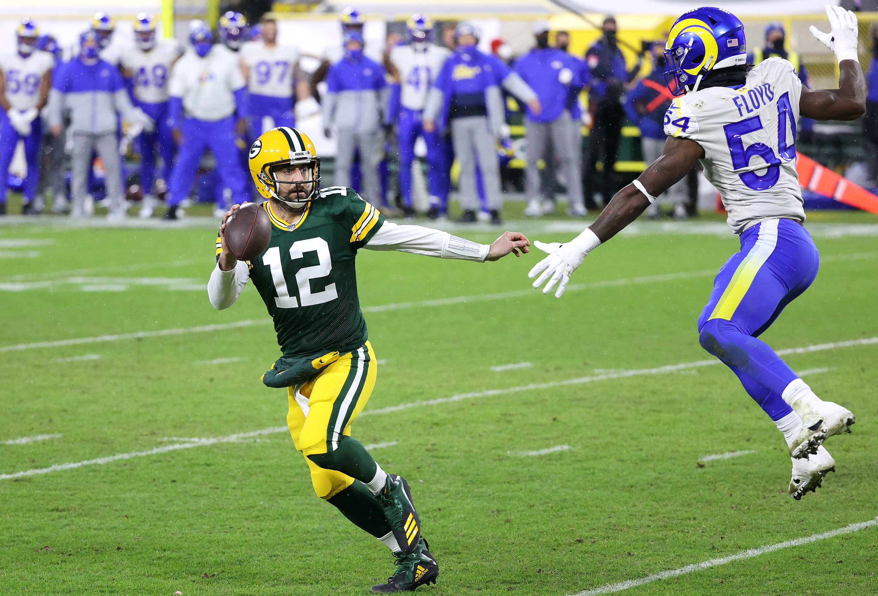 Aaron Rodgers #12 of the Green Bay Packers runs against Leonard Floyd #54 of the Los Angeles Rams for a 1-yard touchdown in the second quarter during the NFC Divisional Playoff game at Lambeau Field on January 16, 2021 in Green Bay, Wisconsin.