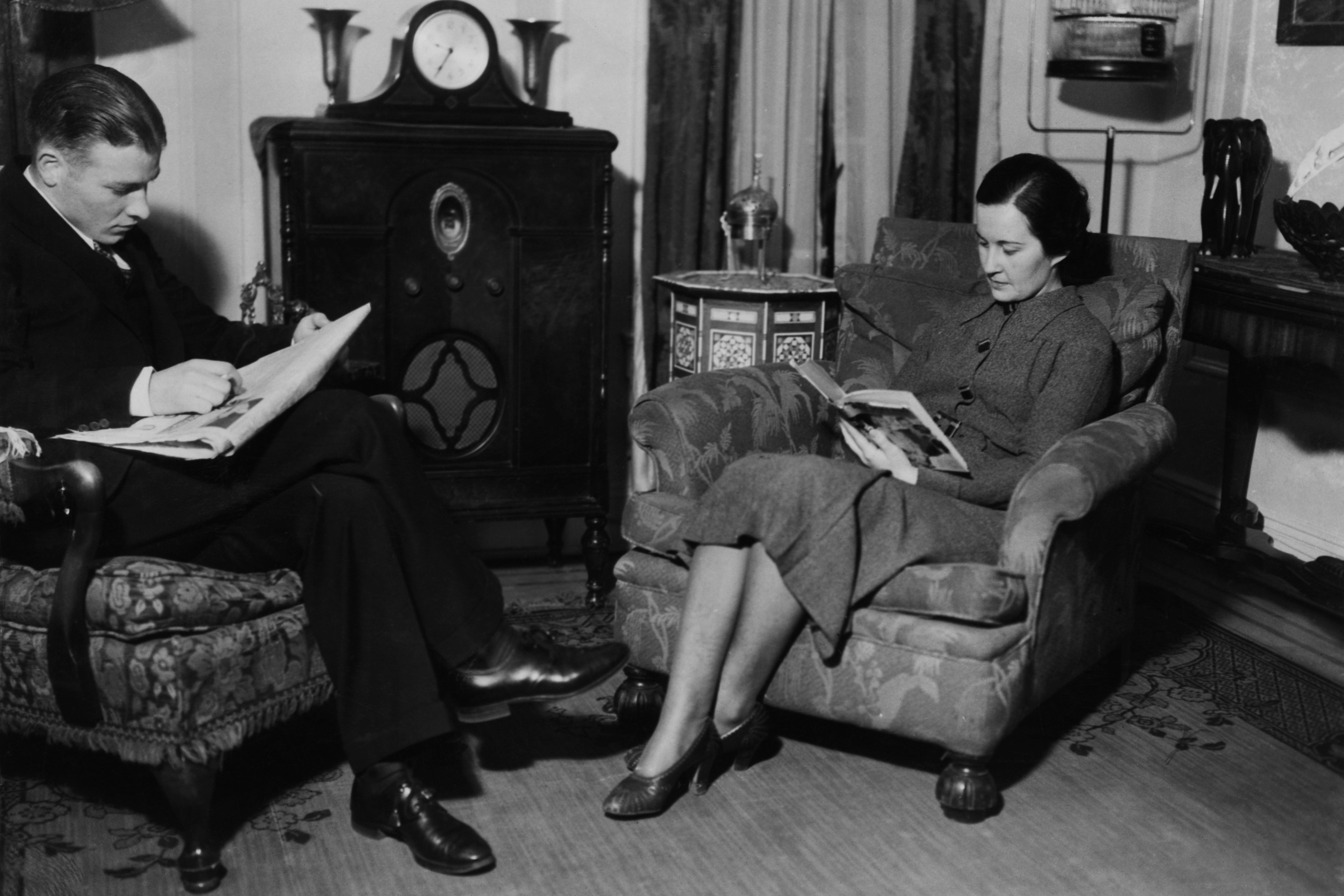 a man and a woman sit in a cozy living room and read