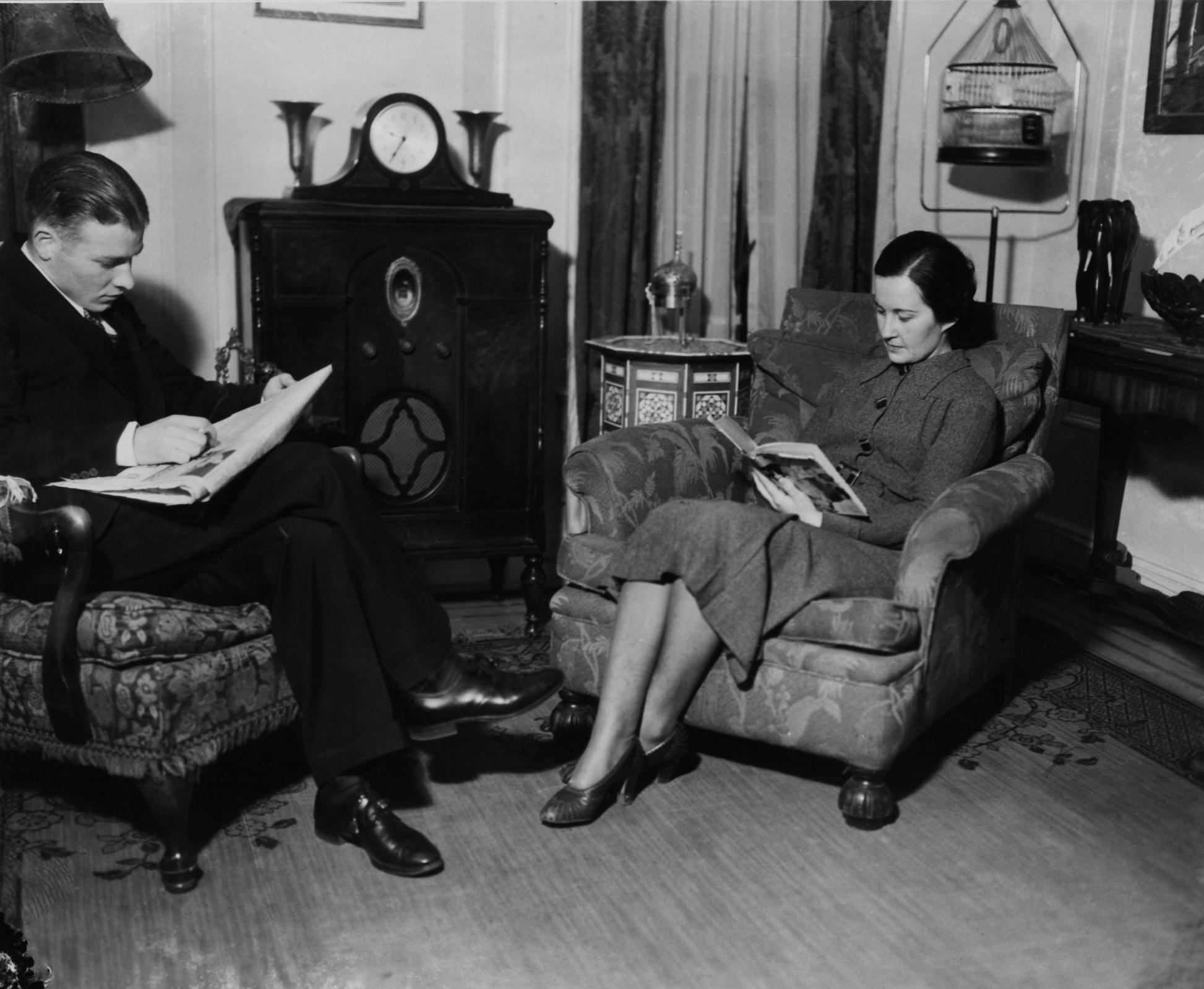 a man and a woman sit in a cozy living room and read