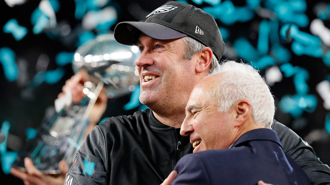At Super Bowl 52, with green and white confetti falling, and the Super BOwl trophy in his hand, Doug Pederson hugs Jeffrey Lurie