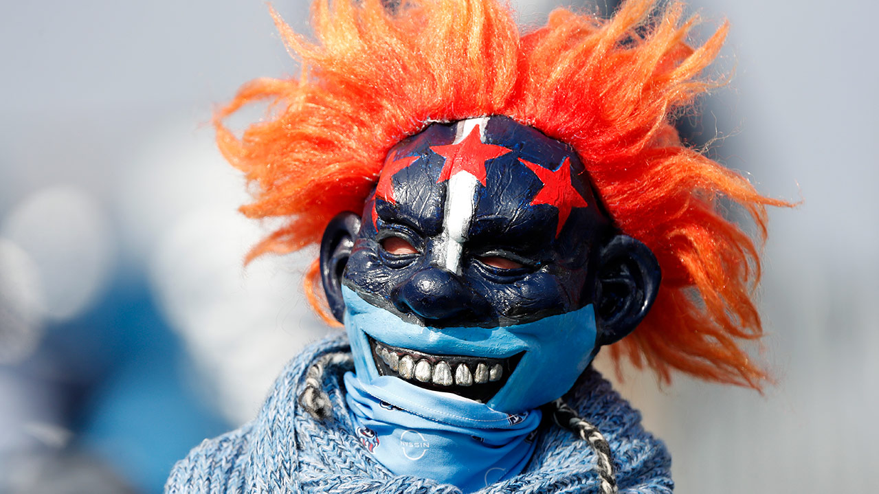 A Tennessee Titans fan wearing a blue mask with the three stars of the Nashville flag on it. He also has wild orange clown hair, and a bandana around his mouth/neck area.