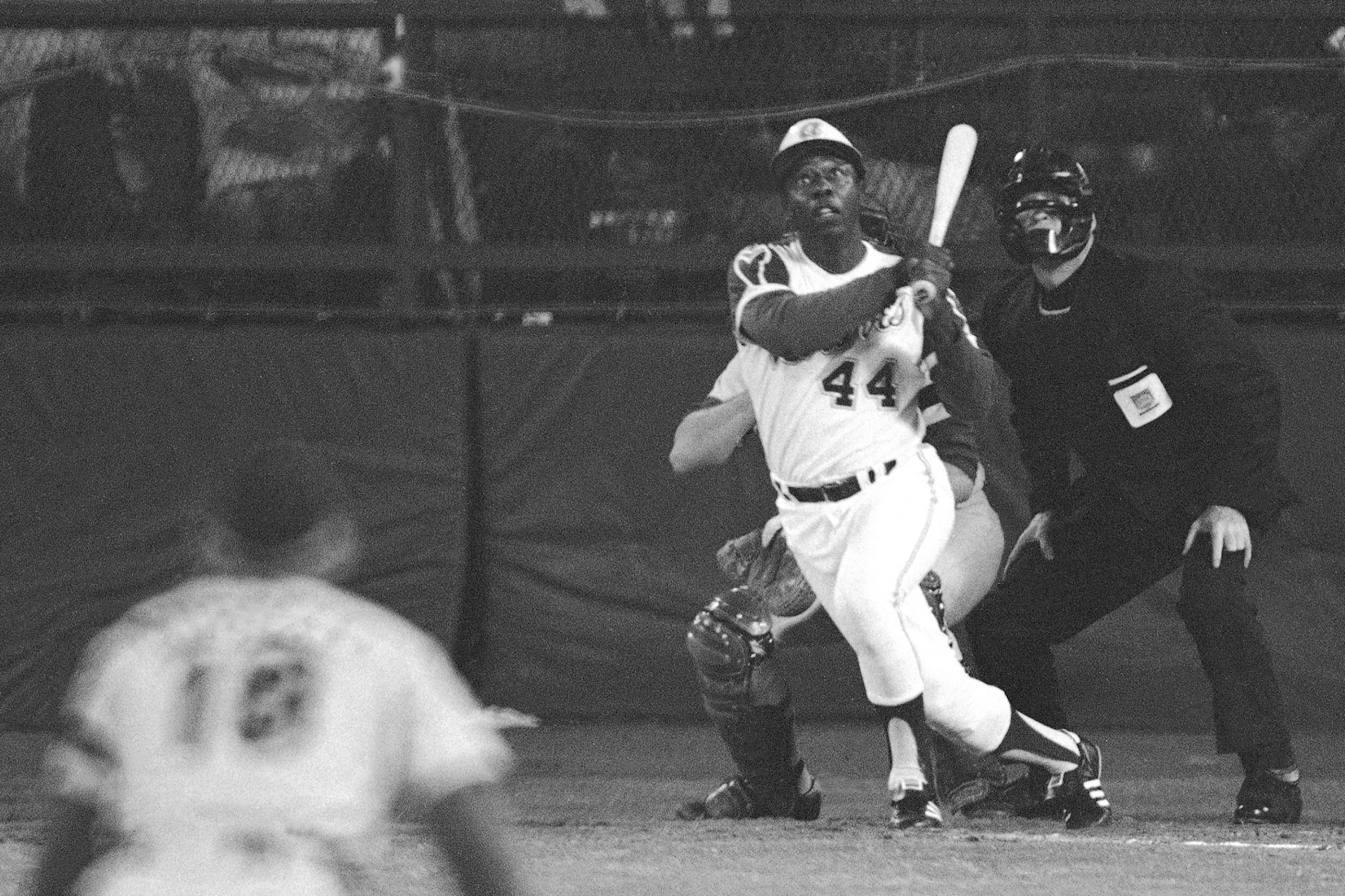 FILE - Atlanta Braves' Hank Aaron eyes the flight of the ball after hitting his 715th career homer in a game against the Los Angeles Dodgers in Atlanta, Ga., in this April 8, 1974 file photo. Dodgers pitcher Al Downing, catcher Joe Ferguson and umpire David Davidson look on. Hank Aaron, who endured racist threats with stoic dignity during his pursuit of Babe Ruth but went on to break the career home run record in the pre-steroids era, died early Friday, Jan. 22, 2021. He was 86. The Atlanta Braves said Aaron died peacefully in his sleep. No cause of death was given. (AP Photo/Harry Harrris, FIle)