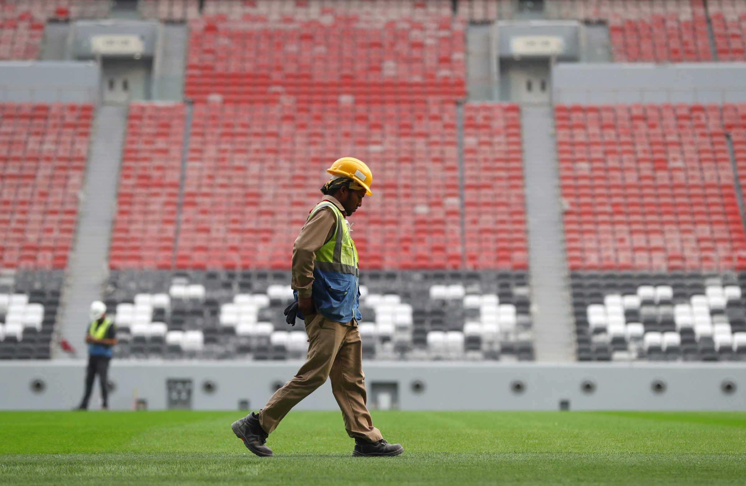 A laborer walks on the field in one of the new stadiums Qatar has constructed for the 2022 World Cup.