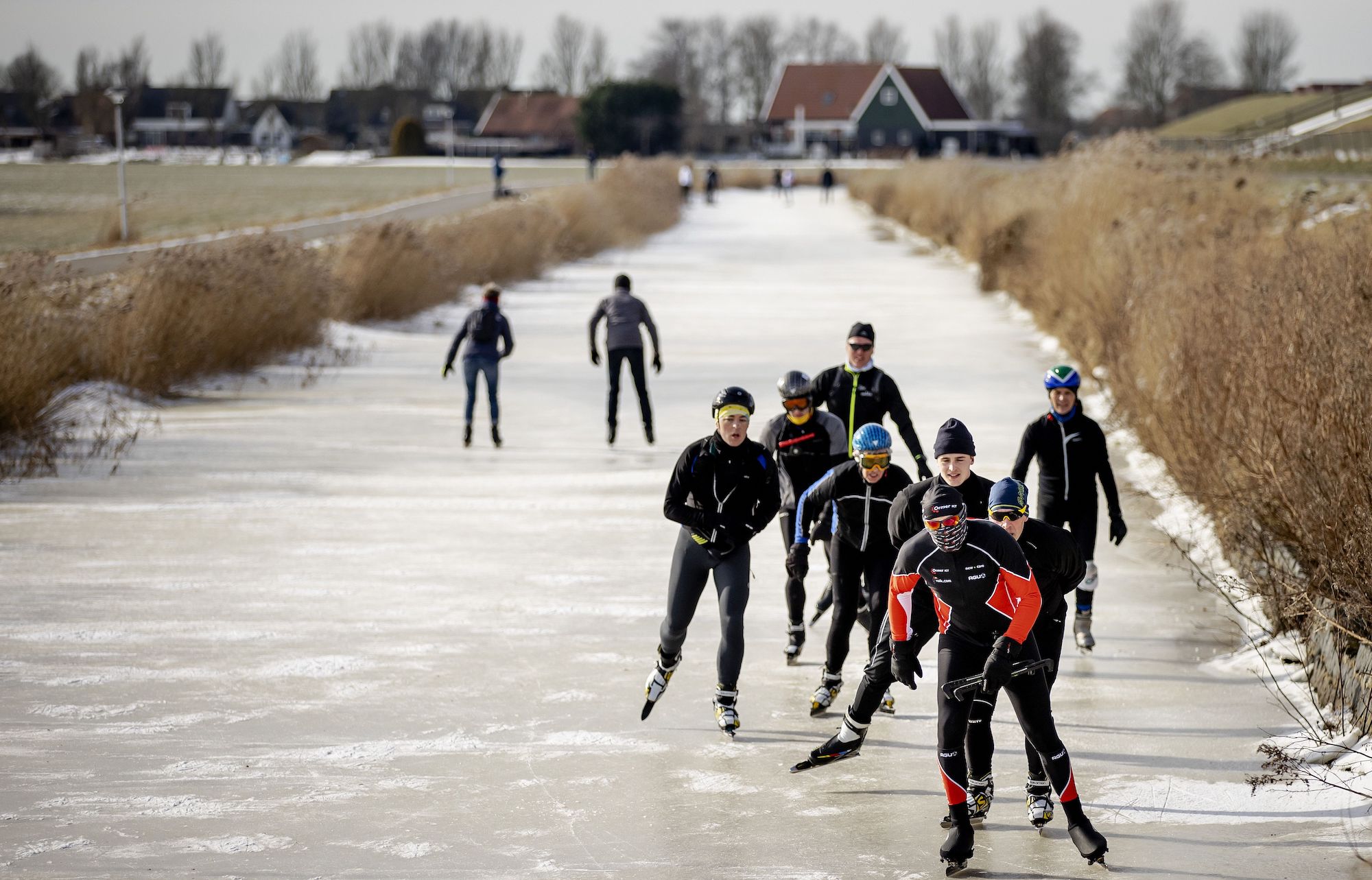 Dutch skater Henk Angenent (C/red/black) is followed by others as he glides across ice on a canal at Hindeloopen on February 14, 2021, as he attempts the 'Elfstedentocht' in the Netherlands' province of Friesland. - Angenent a farmer, who was winner of the last edition of the 'Elfstedentocht' in 1997, which is an organised 200-kilometre skating tour along the 11 Frisian towns and has been adapted to comly with restrictions as part of the ongoing coronavirus (Covid-19) pandemic. (Photo by ROBIN VAN LONKHUIJSEN / ANP / AFP) / Netherlands OUT (Photo by ROBIN VAN LONKHUIJSEN/ANP/AFP via Getty Images)