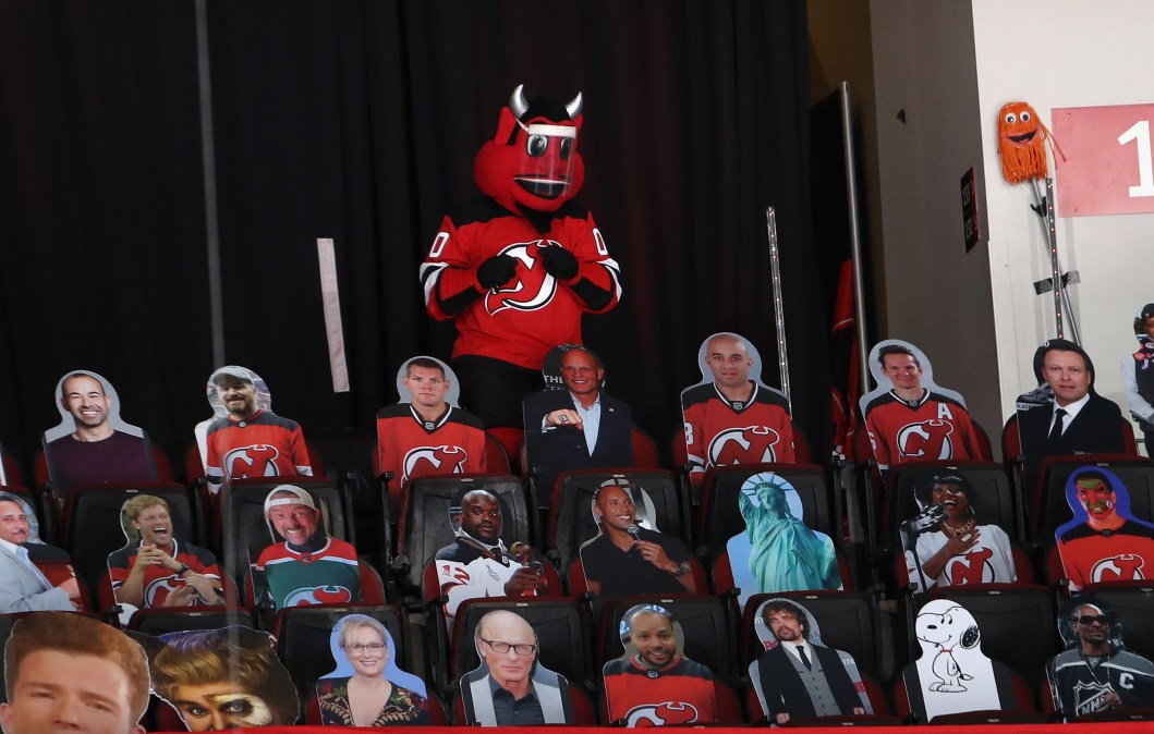 The New Jersey Devil stands in the last row of the arena surrounded by cardboard cut-outs
