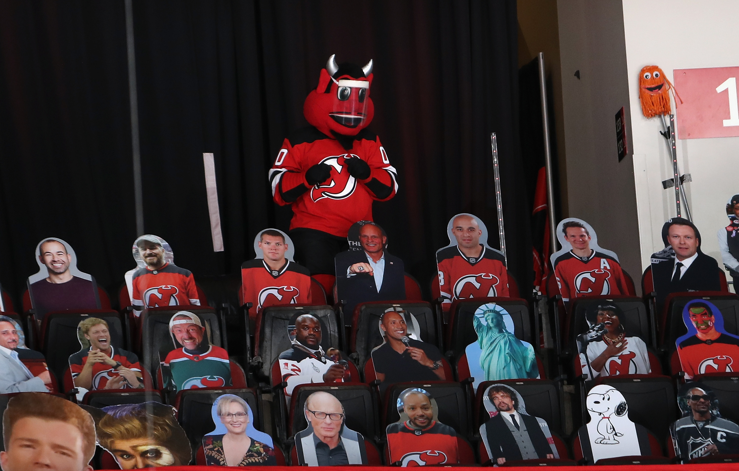The New Jersey Devil stands in the last row of the arena surrounded by cardboard cut-outs