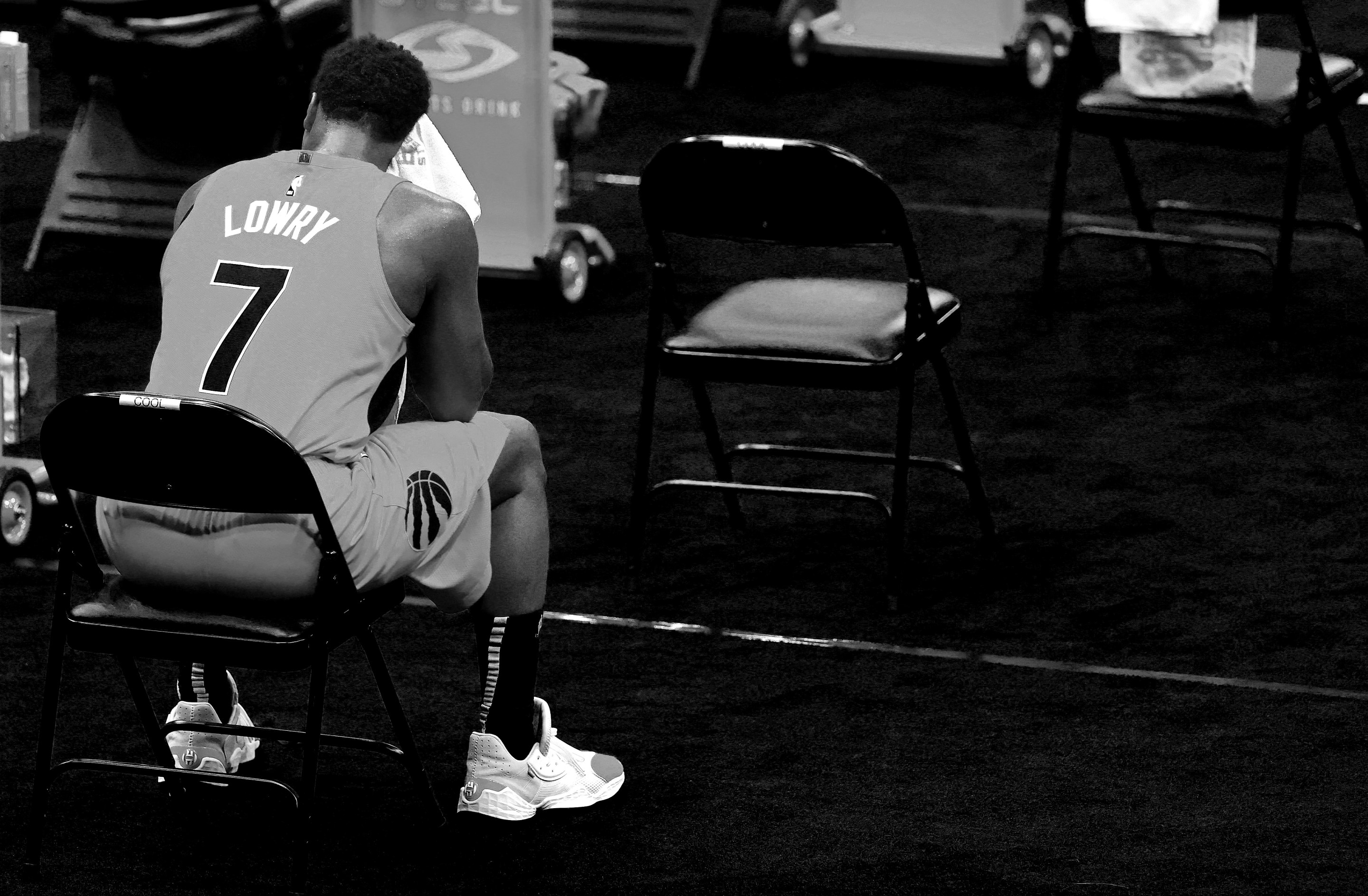 Kyle Lowry sits on the bench in a moody black-and-white image.