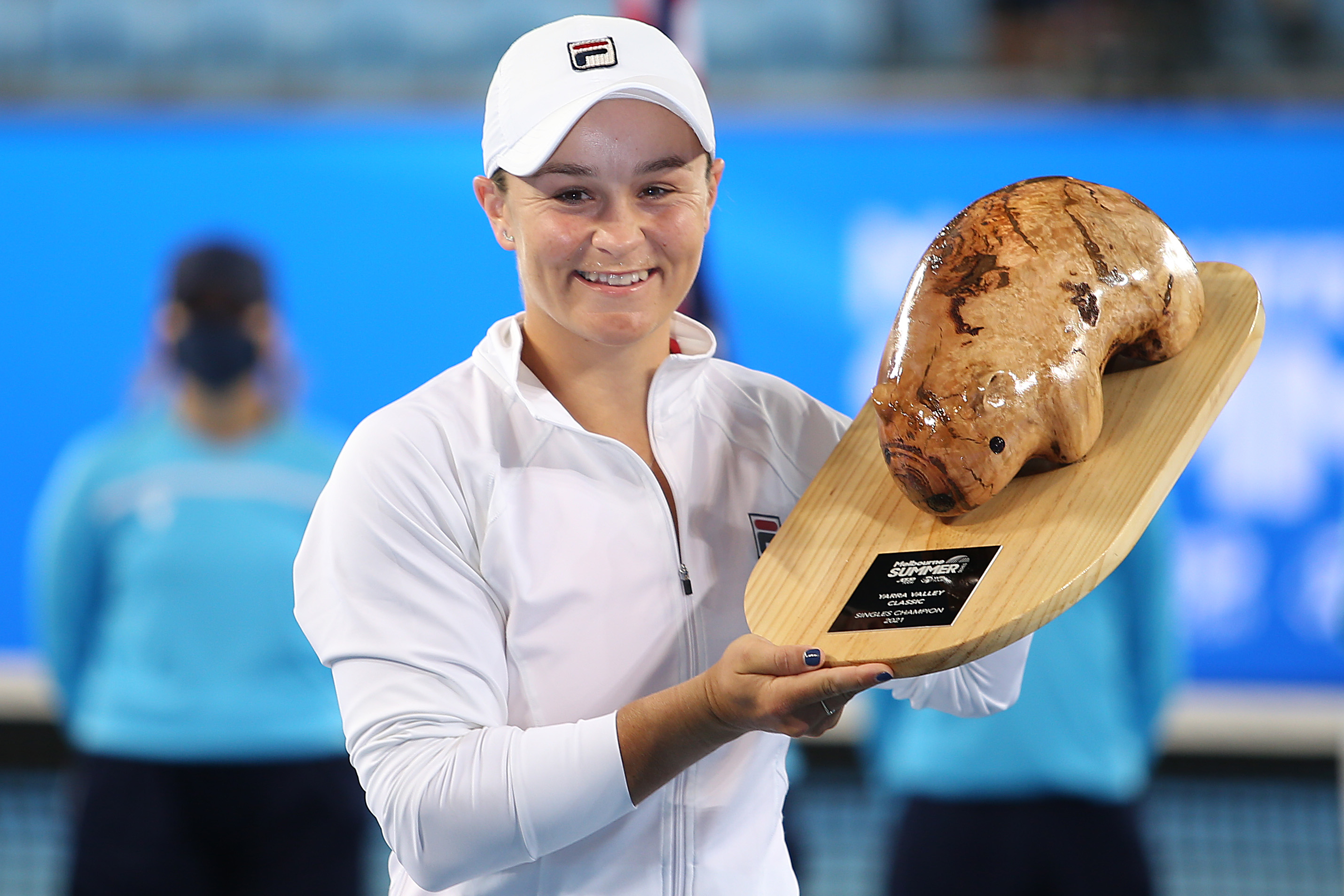Ashleigh Barty holds up a wombat-shaped trophy.