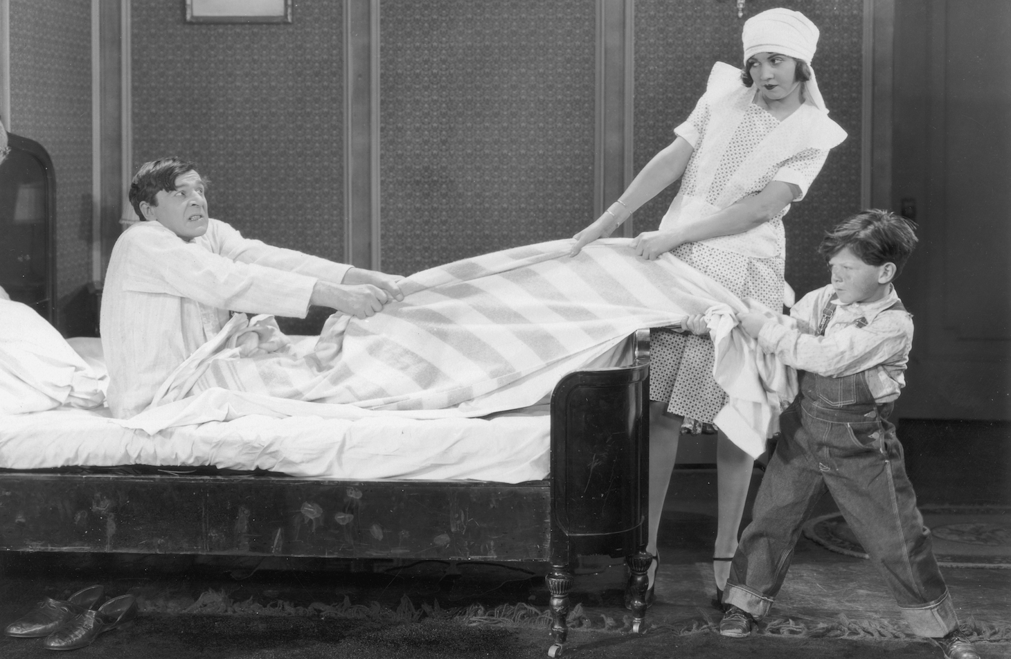 Actors Lucille Hutton and Jackie Levine play tug-of-war with Jack Miller's blanket while attempting to get him out of bed in a still from the silent film comedy 'Oh, Mama'. (Photo by Hulton Archive/Getty Images)