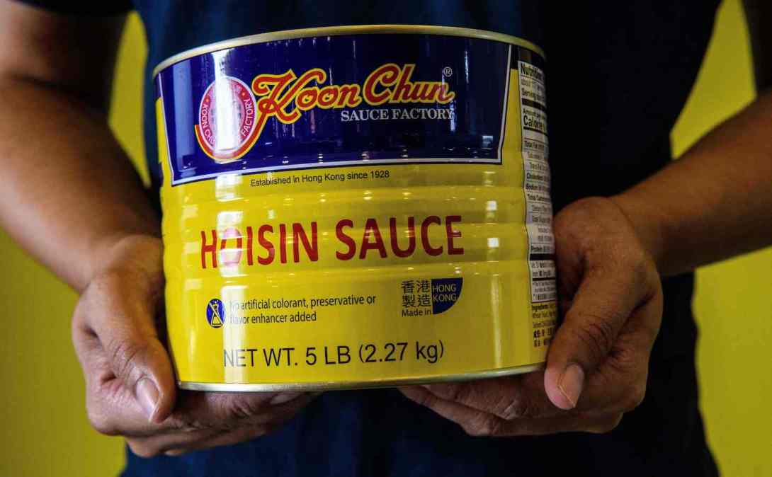 In this picture taken on August 27, 2020, Daniel Chan poses with a tin of Hoisin sauce with labling that reads ÒMade in Hong KongÓ made at the Koon Chun Sauce Factory, founded by his great-grandfather n 1928, in Hong Kong, which produces soy, hoisin and oyster sauces found in Chinese restaurants and kitchens around the world. - At the Koon Chun Sauce Factory workers are scrambling to cover hundreds of thousands of bottles with new "Made in China" labels as the popular Hong Kong brand falls victim to spiralling diplomatic tensions. (Photo by Anthony WALLACE / AFP) / TO GO WITH: HongKong-China-US-politics-economy, FOCUS by Su Xinqi (Photo by ANTHONY WALLACE/AFP via Getty Images)