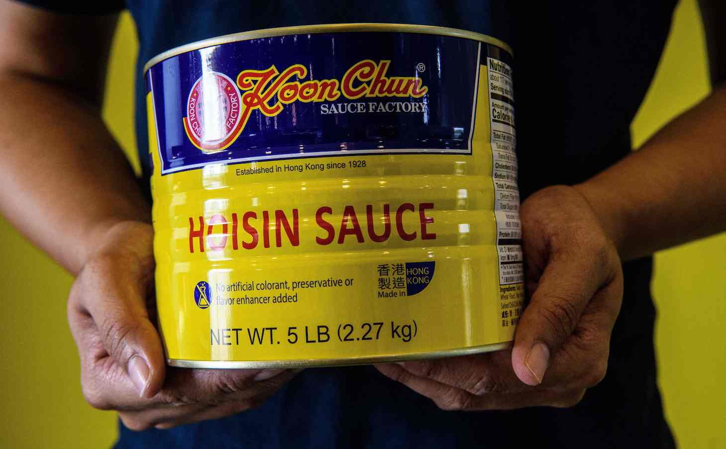 In this picture taken on August 27, 2020, Daniel Chan poses with a tin of Hoisin sauce with labling that reads ÒMade in Hong KongÓ made at the Koon Chun Sauce Factory, founded by his great-grandfather n 1928, in Hong Kong, which produces soy, hoisin and oyster sauces found in Chinese restaurants and kitchens around the world. - At the Koon Chun Sauce Factory workers are scrambling to cover hundreds of thousands of bottles with new "Made in China" labels as the popular Hong Kong brand falls victim to spiralling diplomatic tensions. (Photo by Anthony WALLACE / AFP) / TO GO WITH: HongKong-China-US-politics-economy, FOCUS by Su Xinqi (Photo by ANTHONY WALLACE/AFP via Getty Images)
