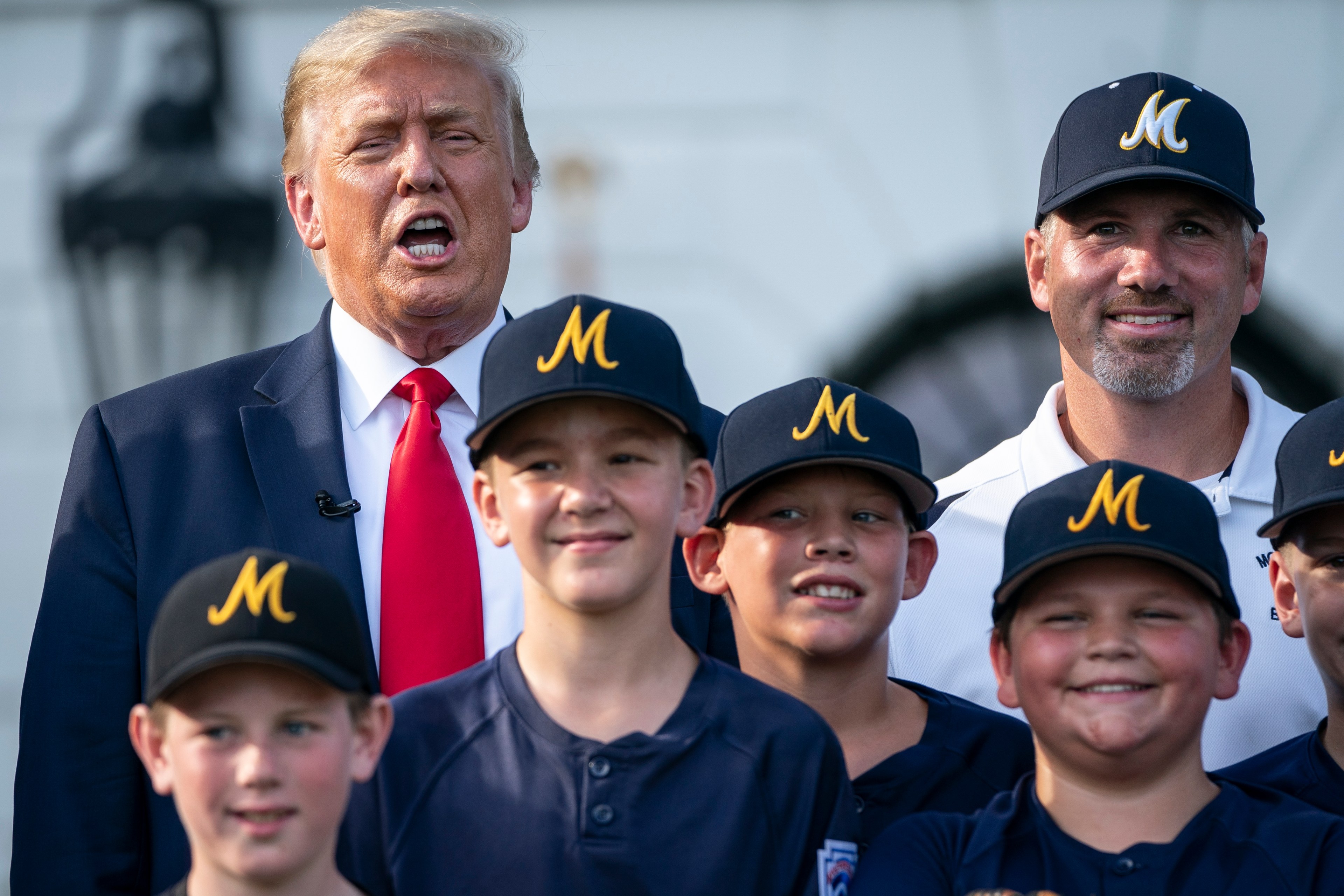 Donald Trump yelling something while posing for a photo with some Little League kids, in 2020.
