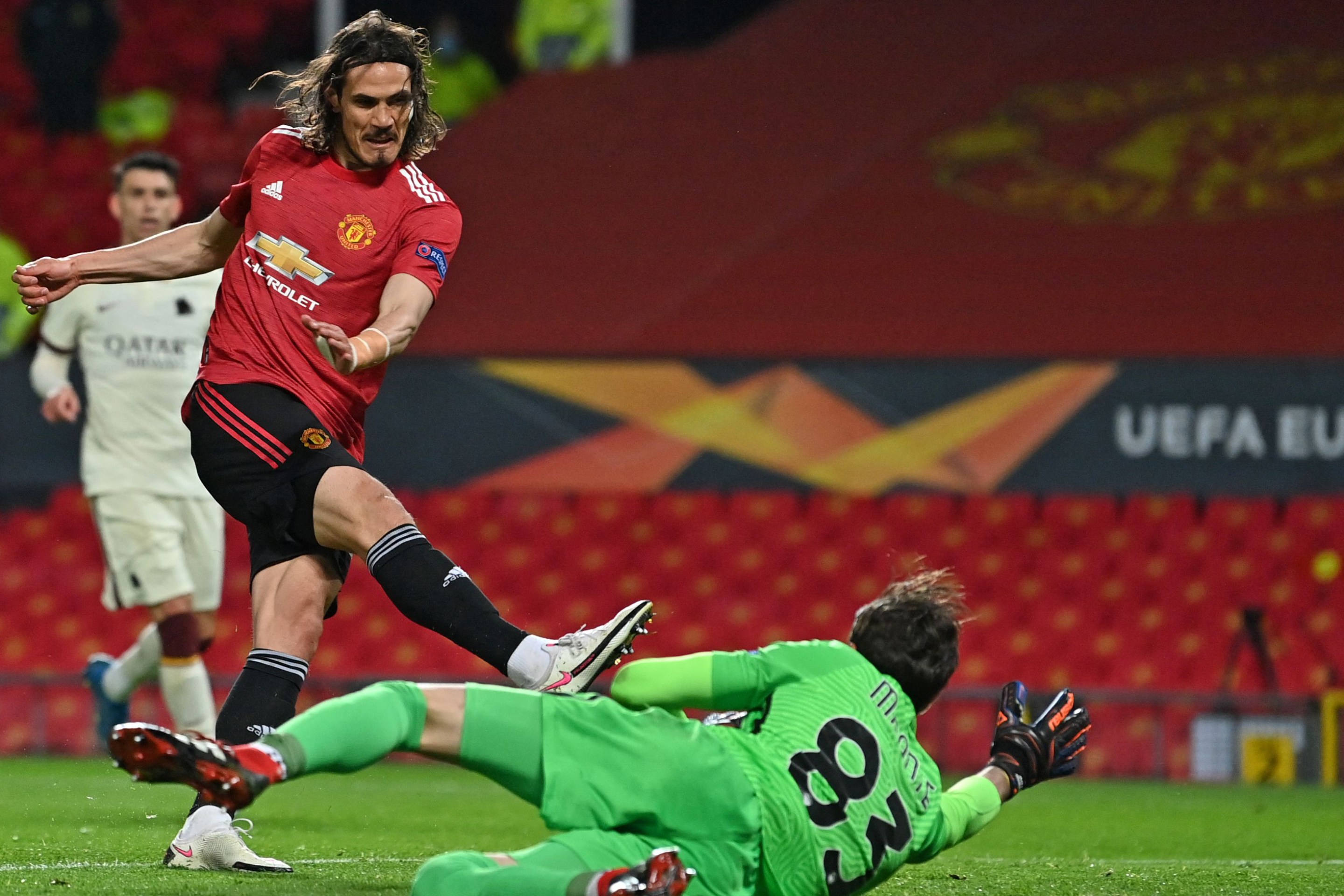 Manchester United's Uruguayan striker Edinson Cavani (L) shoots past Roma's Italian goalkeeper Antonio Mirante to score their third goal during the UEFA Europa League semi-final, first leg football match between Manchester United and Roma at Old Trafford stadium in Manchester, north west England, on April 29, 2021.