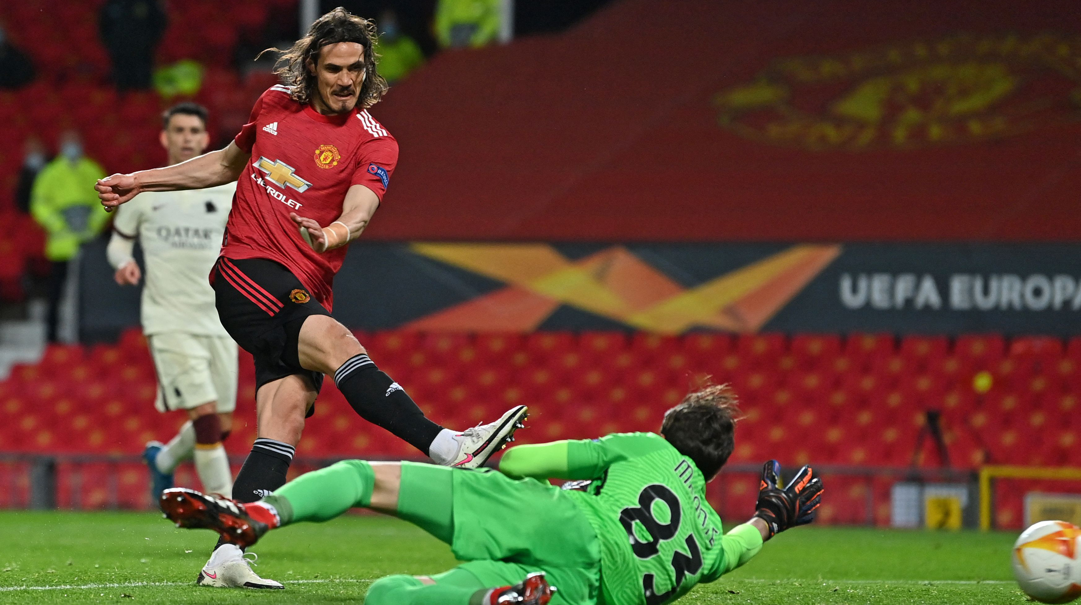 Manchester United's Uruguayan striker Edinson Cavani (L) shoots past Roma's Italian goalkeeper Antonio Mirante to score their third goal during the UEFA Europa League semi-final, first leg football match between Manchester United and Roma at Old Trafford stadium in Manchester, north west England, on April 29, 2021.