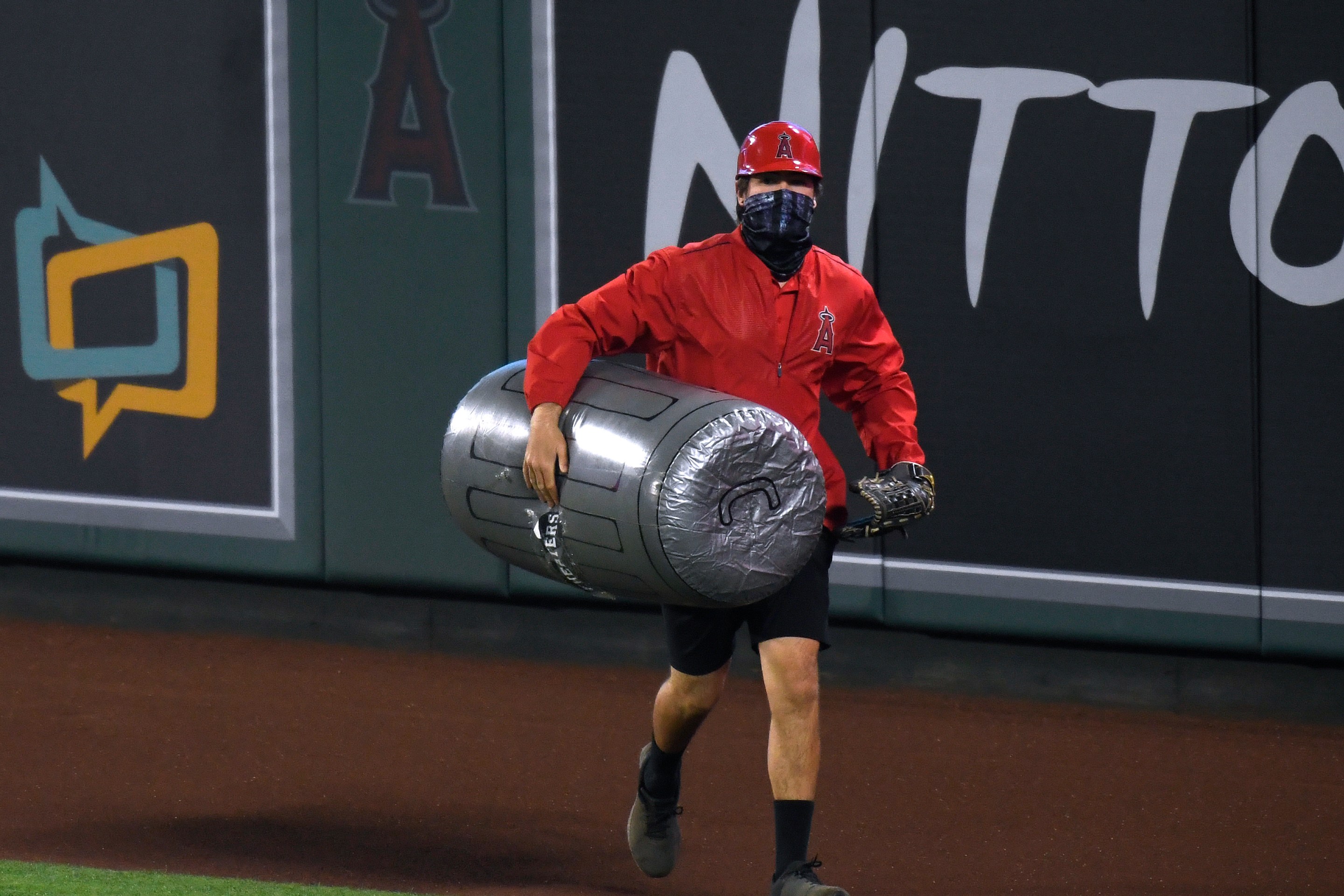 A stadium worker removes a large inflatable trash can prop from the field.