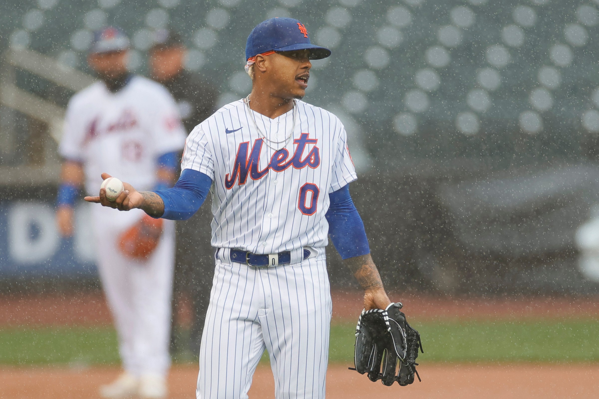 Marcus Stroman of the Mets stands on the mound while it rains.