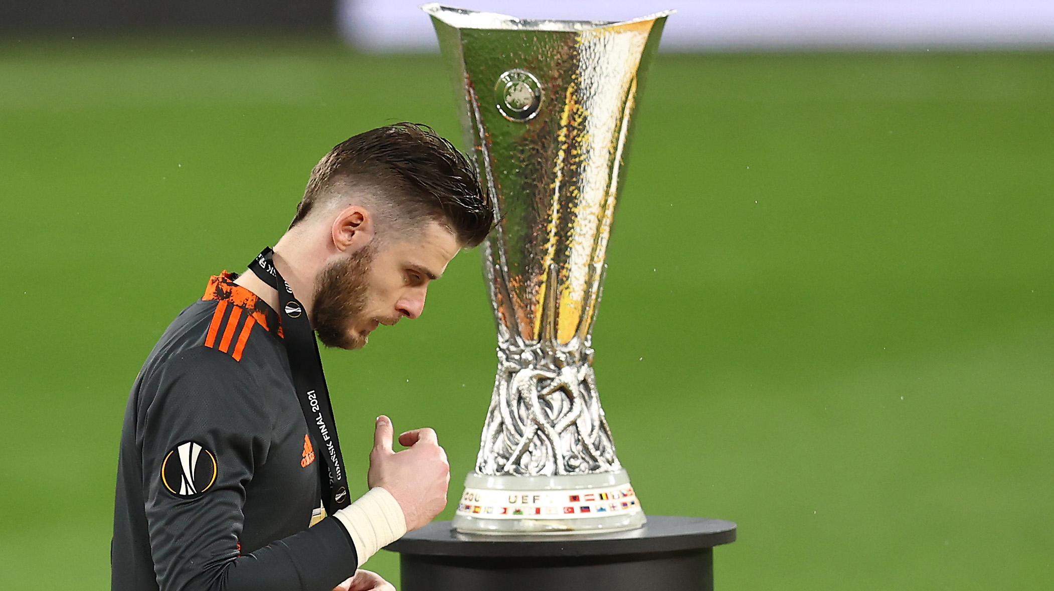 David De Gea of Manchester United removes their medal as they make their way past the UEFA Europa League Trophy following the UEFA Europa League Final between Villarreal CF and Manchester United at Gdansk Arena on May 26, 2021 in Gdansk, Poland